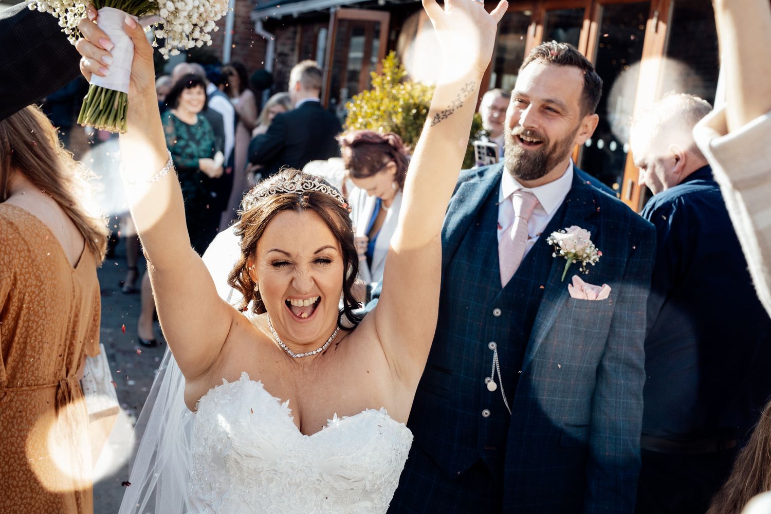 A joyful wedding celebration moment captured with raised hands and bright smiles.