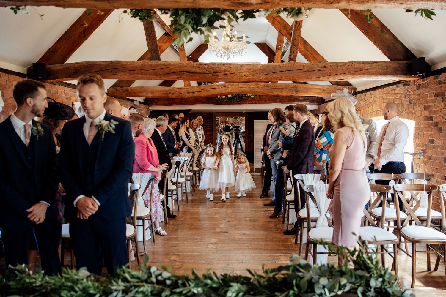 Wedding ceremony setup in a rustic barn venue with exposed wooden beams and brick walls.