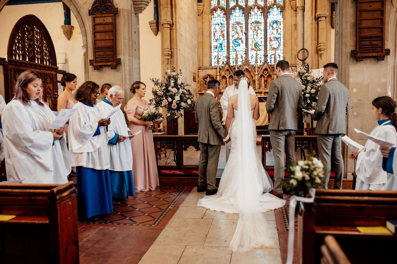 A traditional church wedding ceremony with stained glass windows and wooden pews.