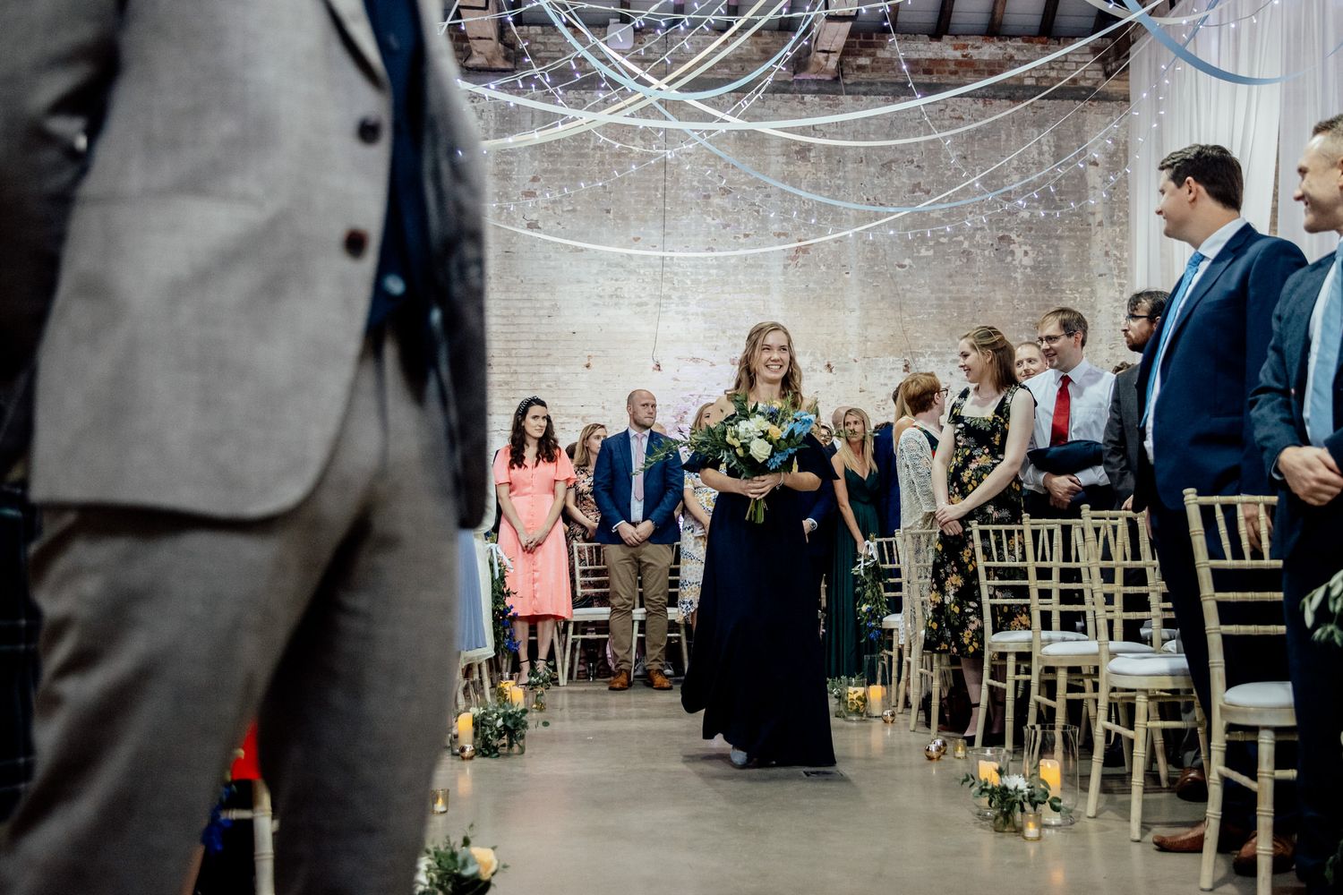 Wedding ceremony setup with exposed brick walls and elegant gold chairs in an industrial venue.