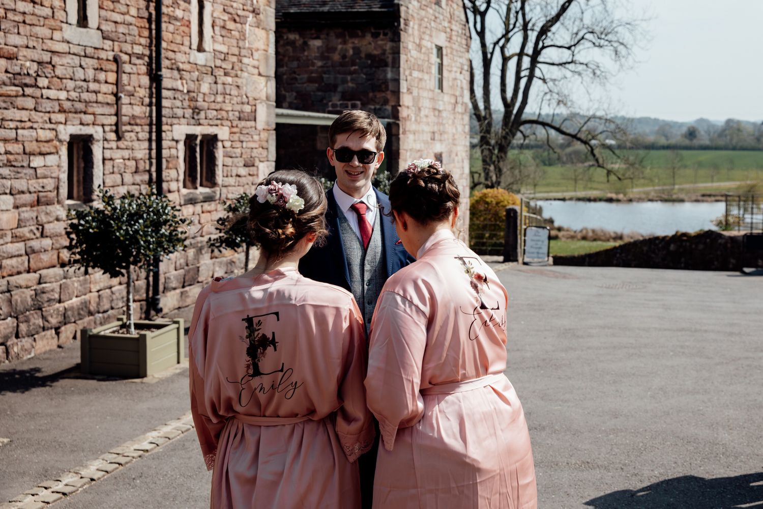 Wedding party in matching pink outfits standing outside historic brick building.
