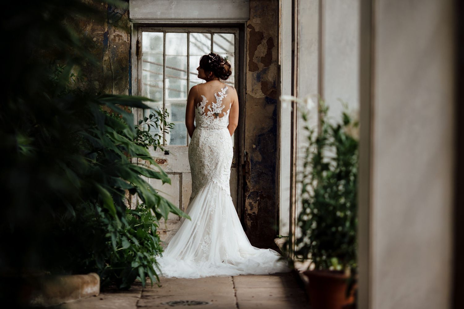 Wedding dress displayed in rustic venue with natural window light and greenery.