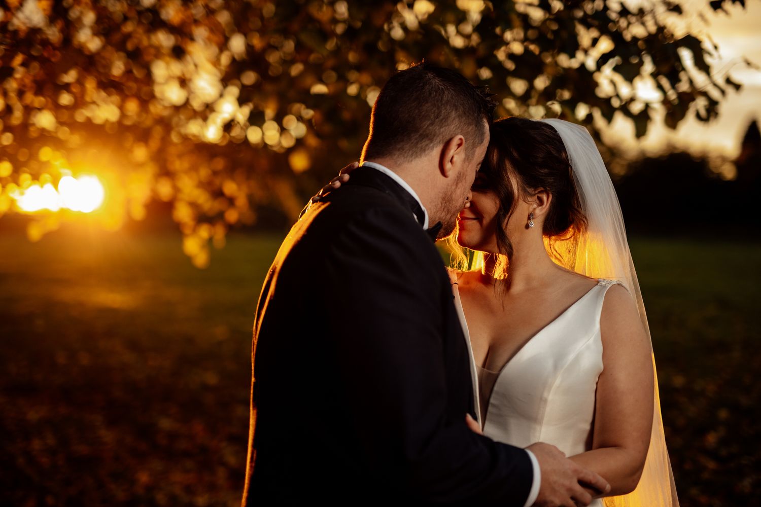 Sunset wedding portraits with golden light filtering through autumn trees.