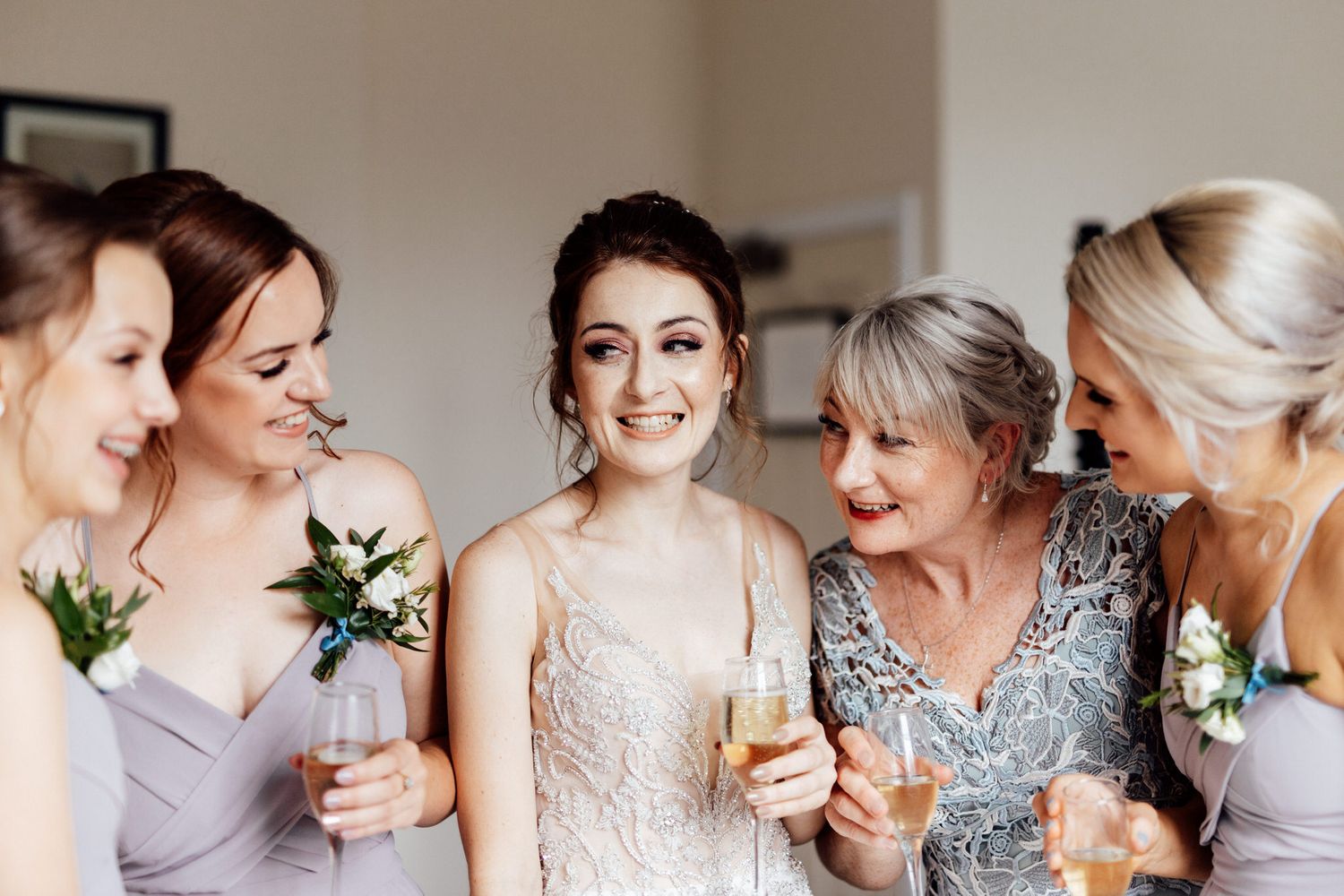 Group sharing joyful moment while getting ready in bridal suite.