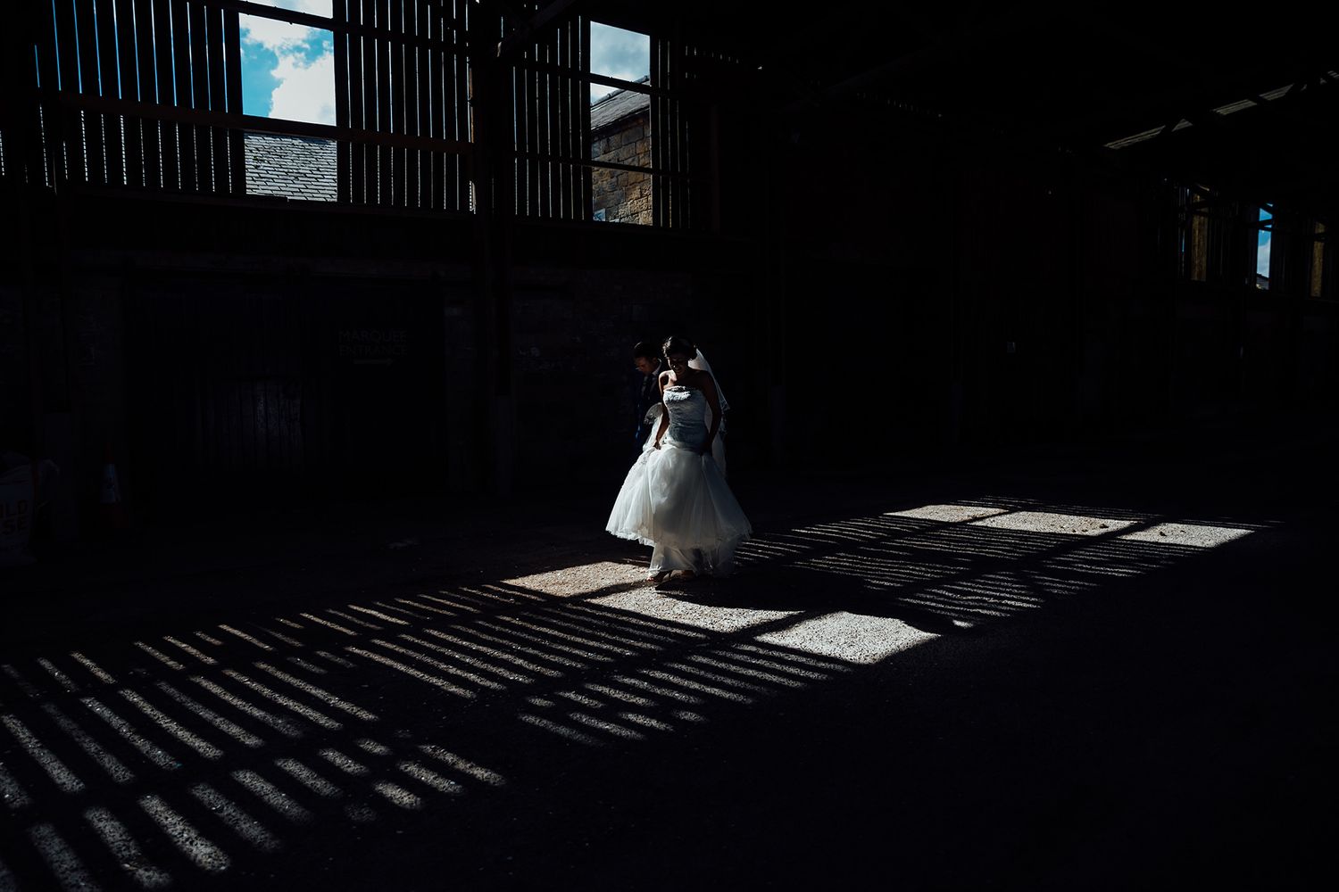 Dramatic shadows cast through barn slats create striking patterns on the floor.