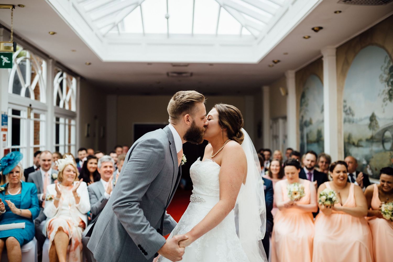 Elegant wedding ceremony takes place in a bright conservatory with glass ceiling.