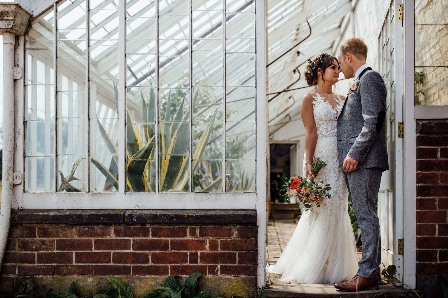 Wedding couple sharing intimate moments in a beautiful greenhouse setting.