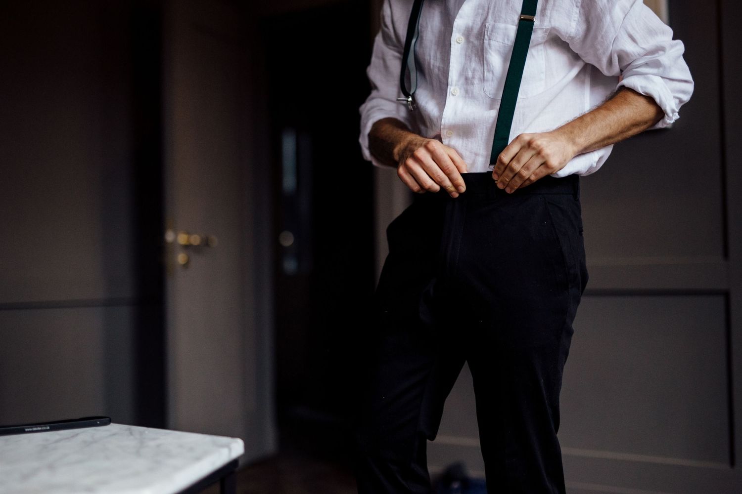 Close-up detail of formal attire showing suspenders and white dress shirt.