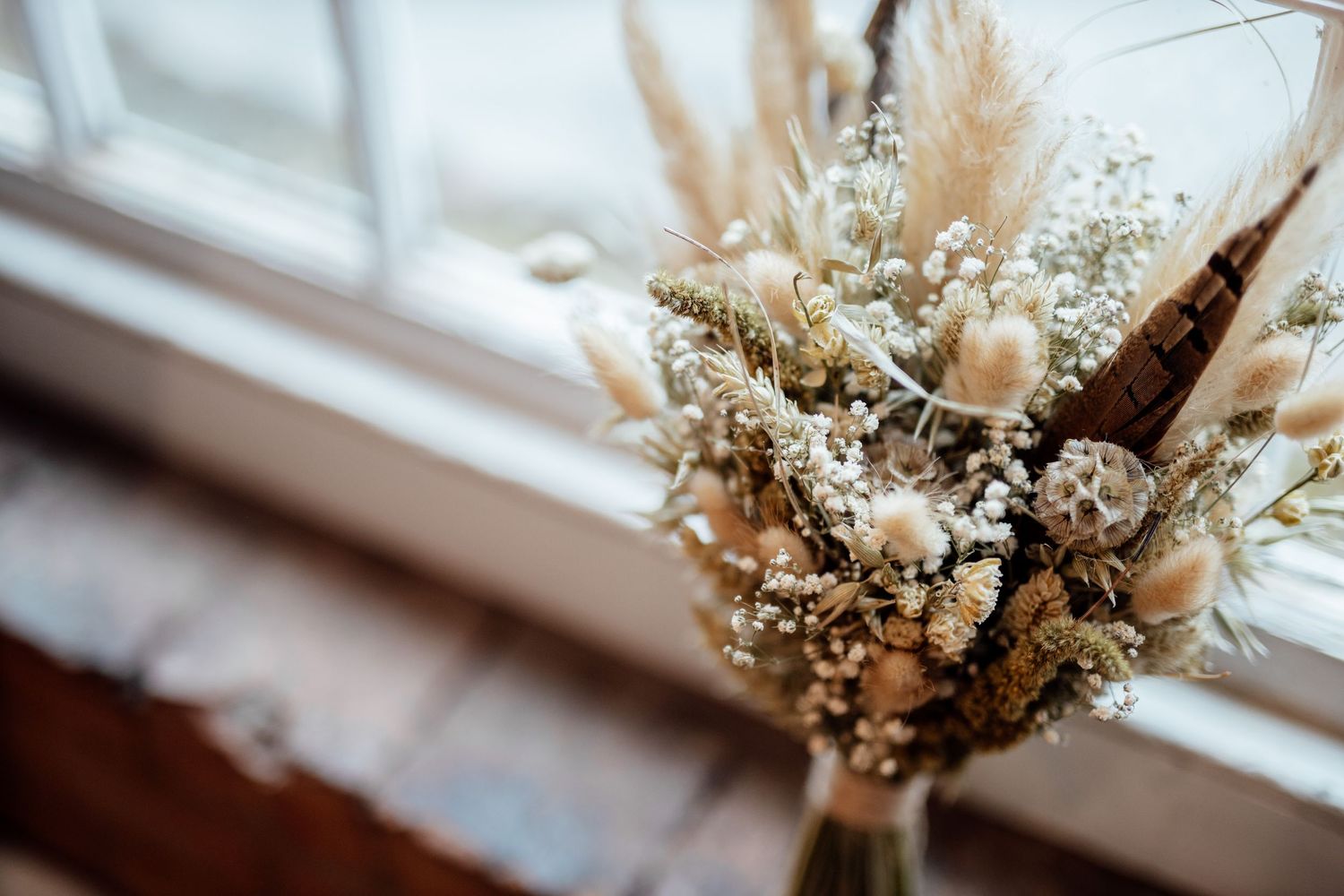 Dried flower and pampas grass wedding decoration details in window light.