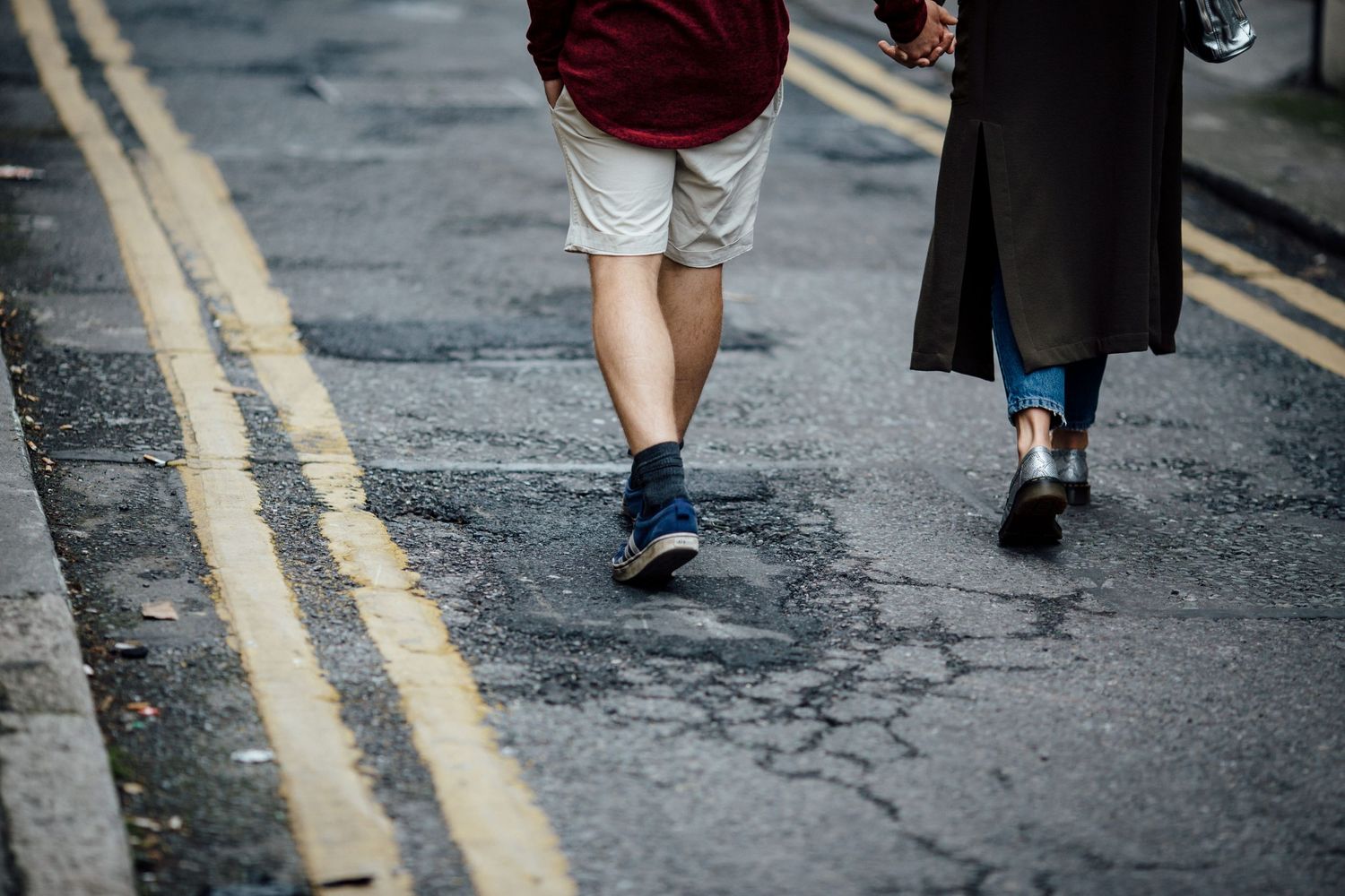 Street level view of people walking on urban pavement with yellow line markings.
