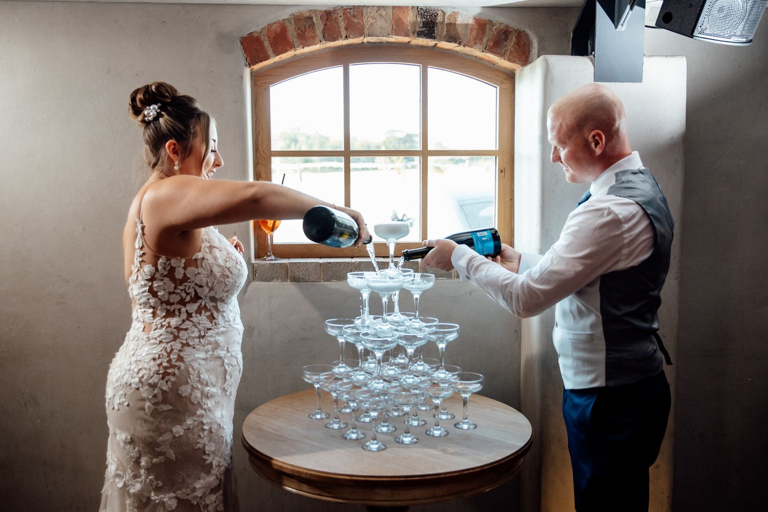 Champagne tower being carefully assembled at elegant wedding reception.