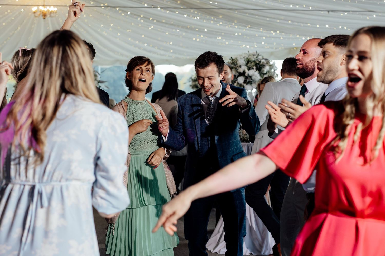 Lively dance floor scene with wedding guests enjoying celebration.