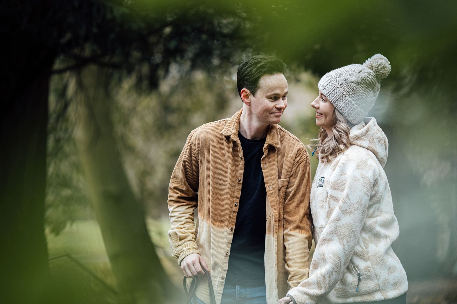 Artistic portrait through foliage showing a tender moment between a couple.