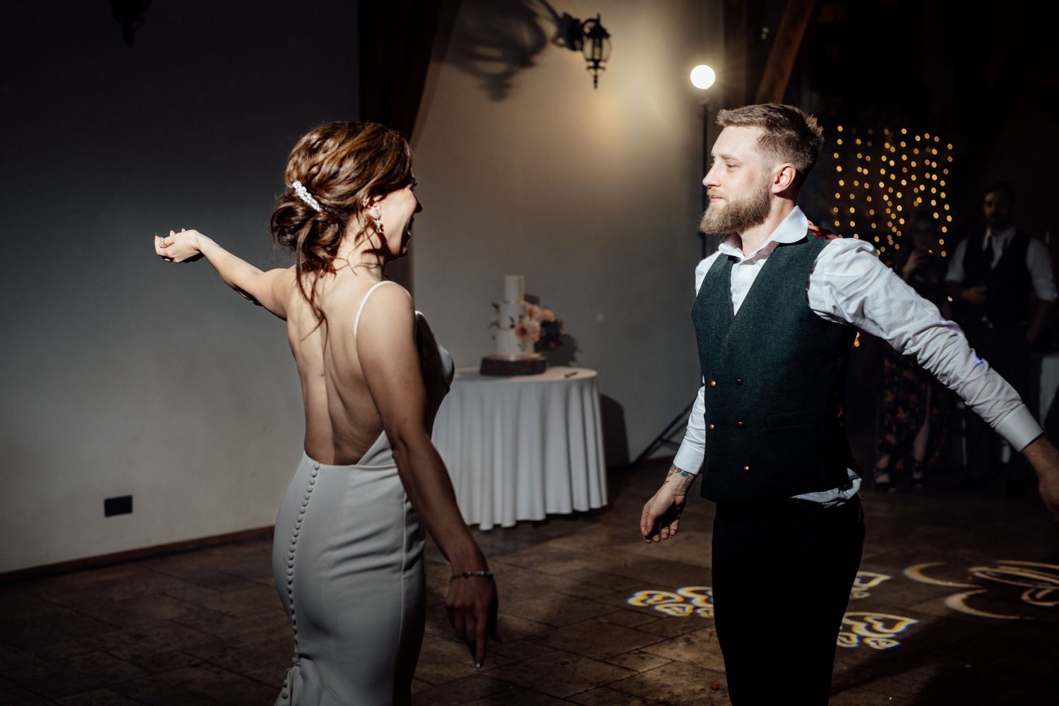 Wedding reception dance floor with guests dancing in dark room with string lights.