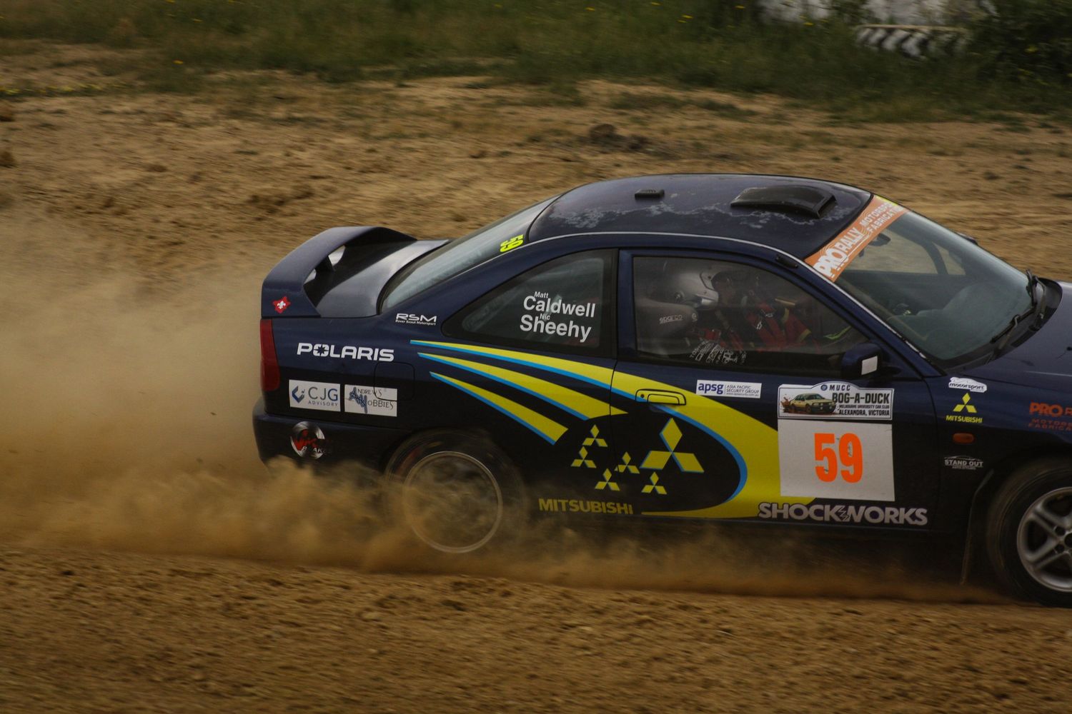 Rally cars competing on dirt track with dust clouds trailing behind.
