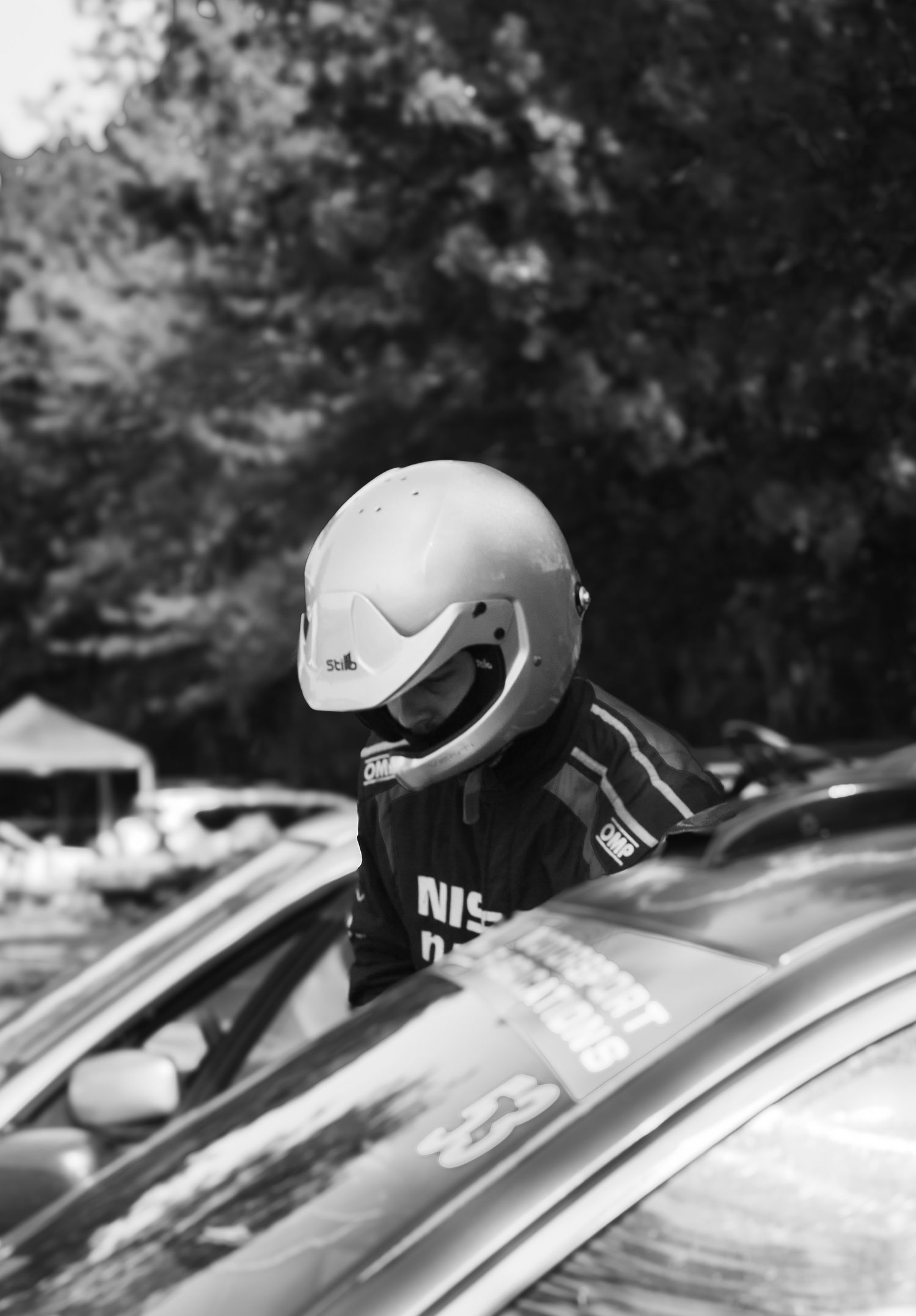 White racing helmet resting on car roof in monochrome photography.