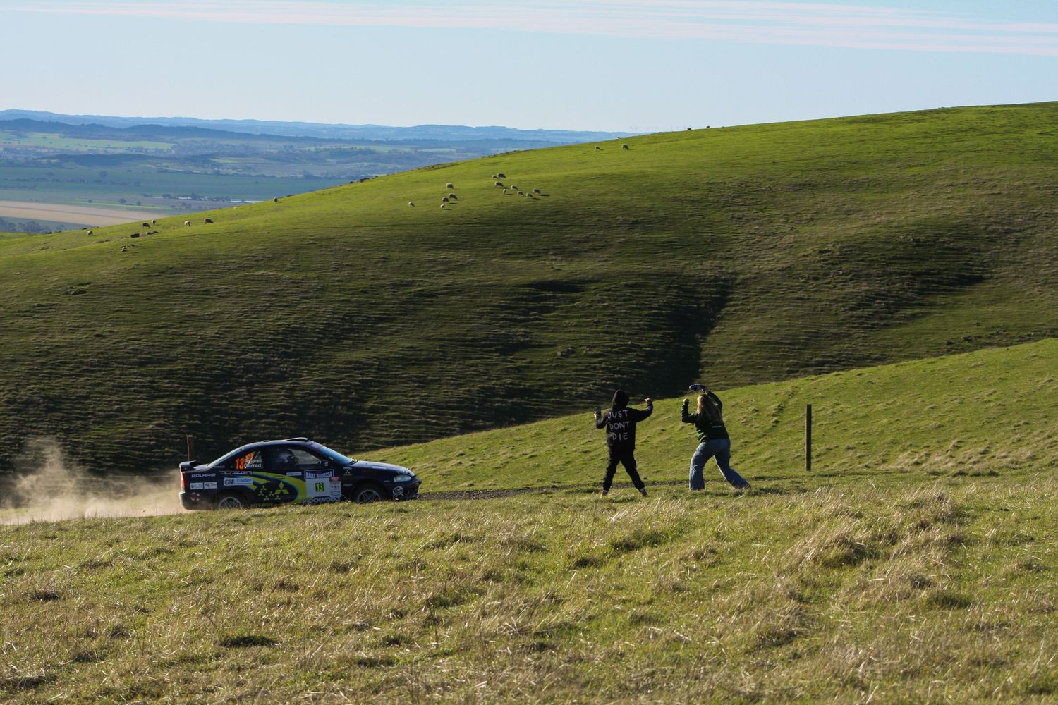 Rolling green hills stretch into the distance under a bright blue sky.