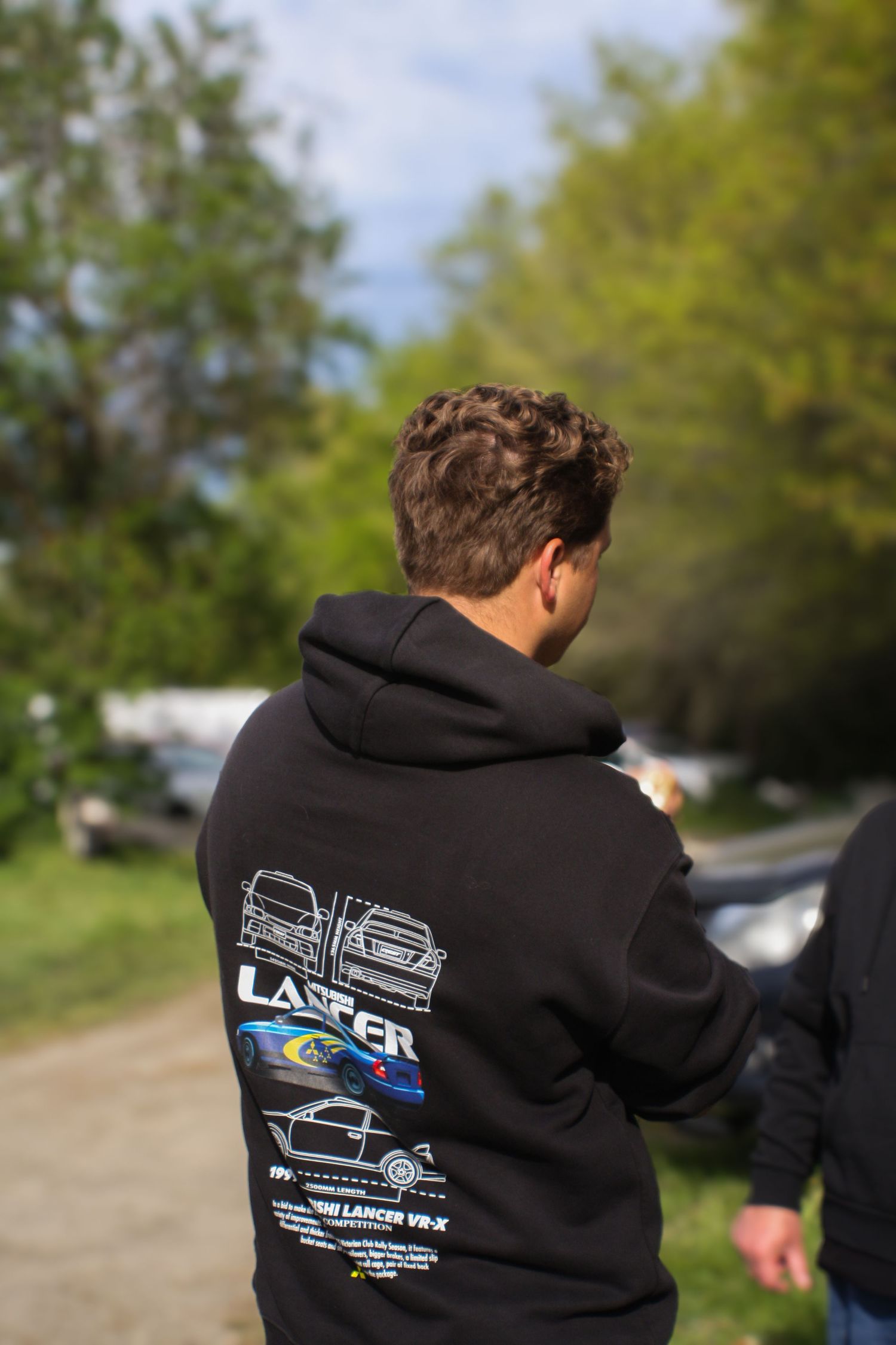 Black hoodie with custom Mitsubishi Lancer Evolution design worn at automotive event.