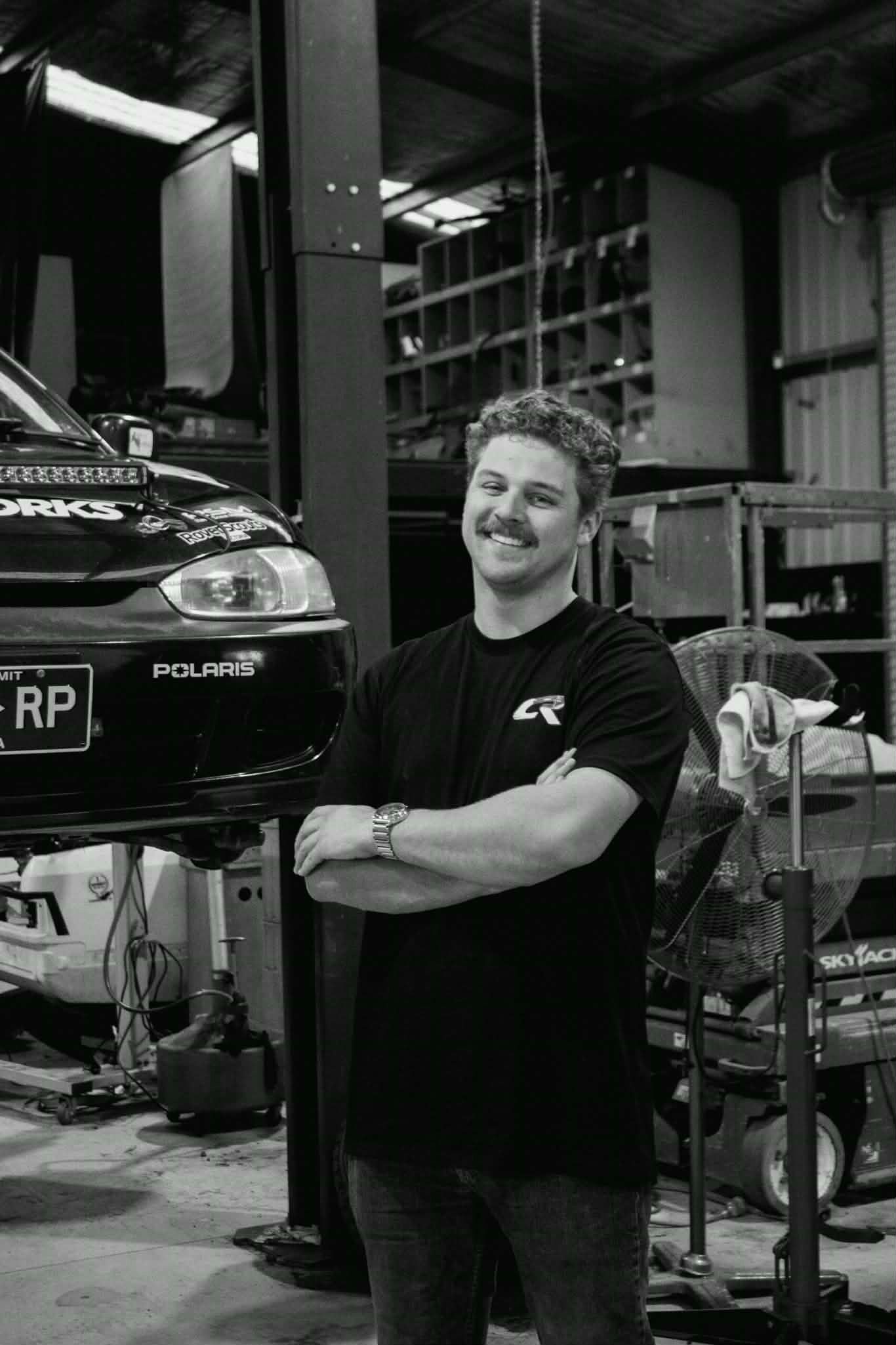 Auto repair shop interior with Subaru race car visible in the workspace.