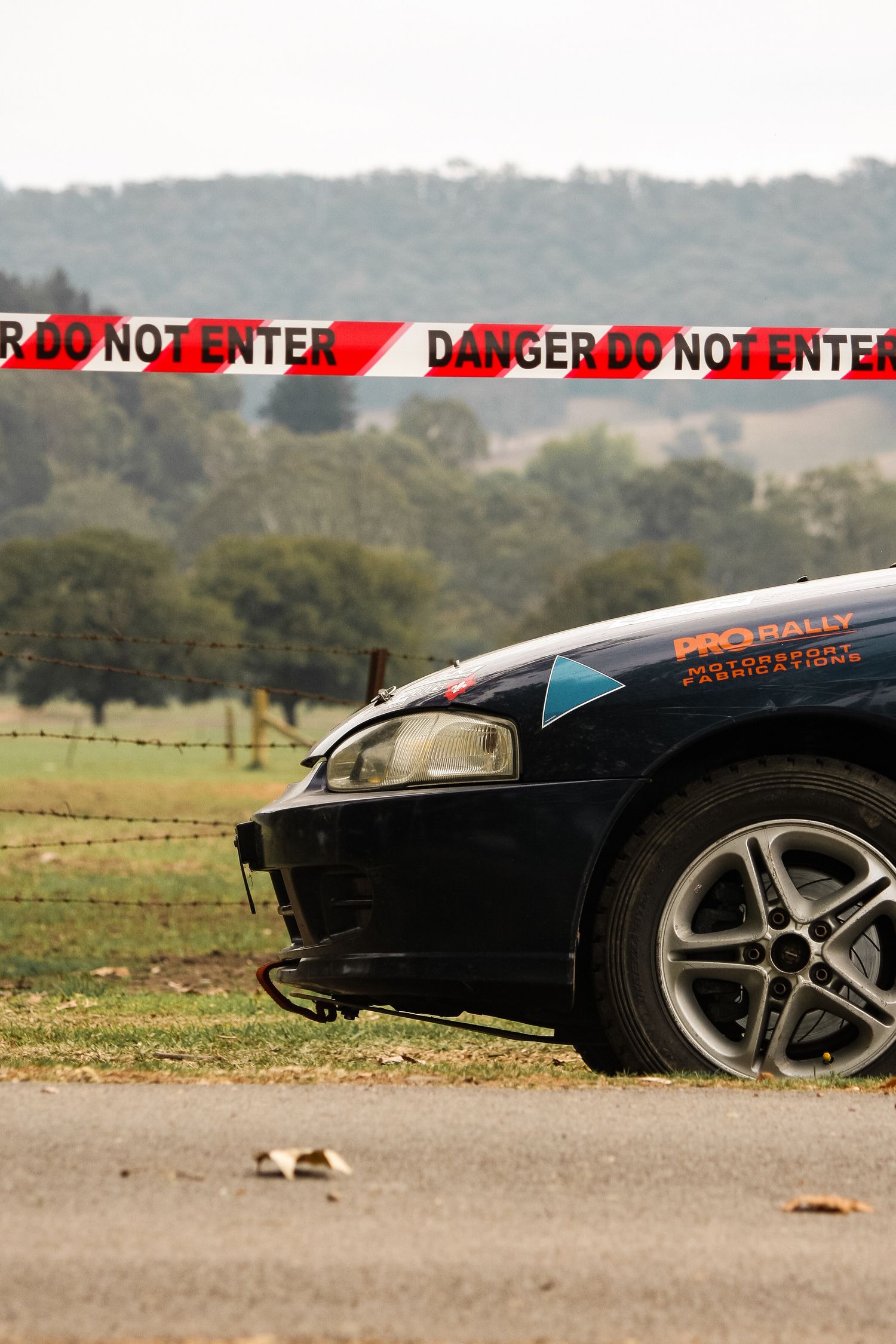 Low angle view of black sports car with danger warning tape visible.