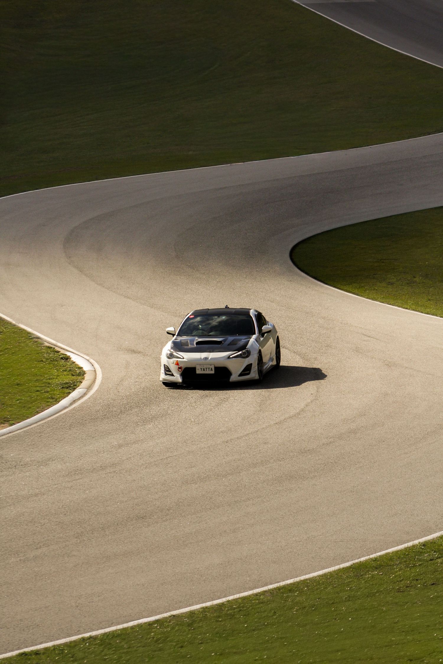 Sports cars navigate a curved racetrack section during a track day event.