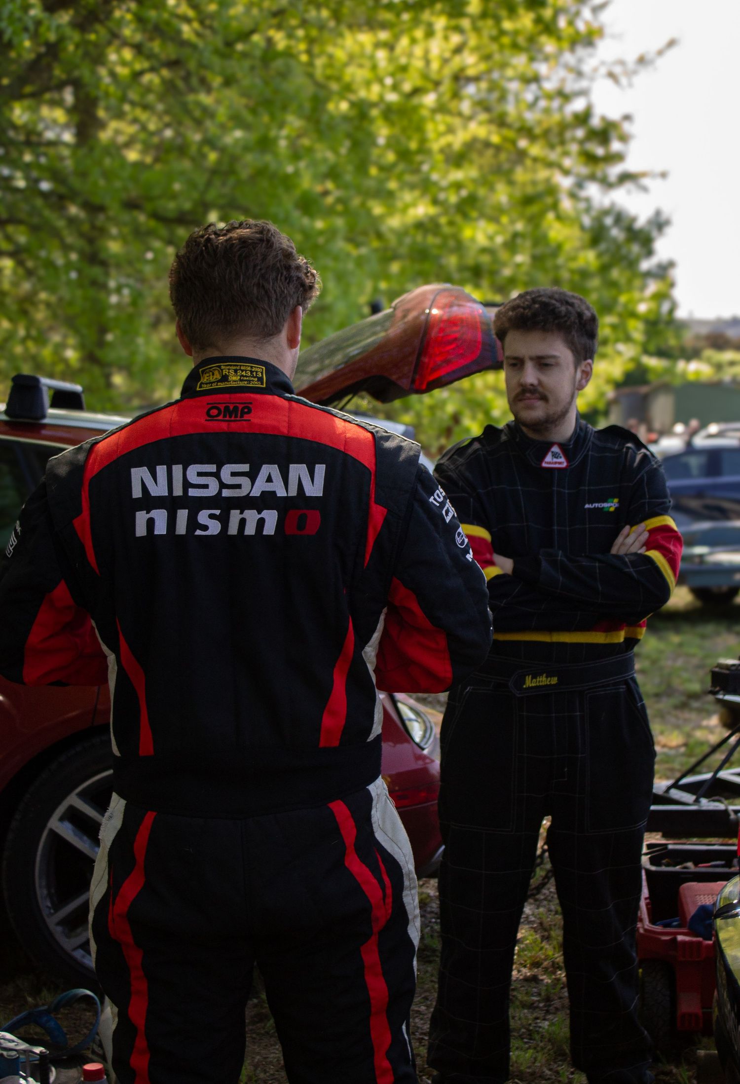 Racing team members in Nissan NISMO uniforms working outdoors at motorsport event.