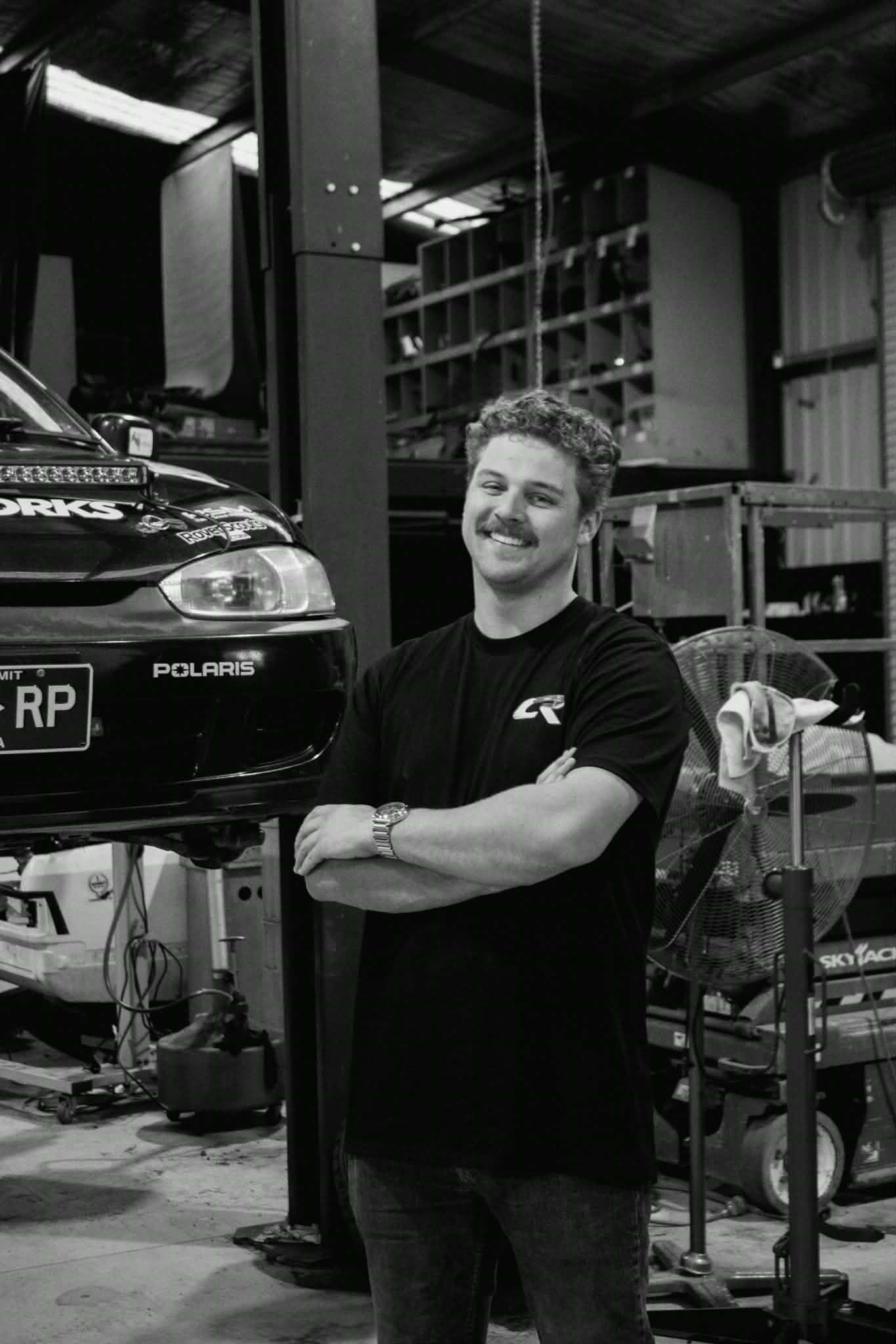 Professional automotive workshop interior with mechanics and performance vehicles.