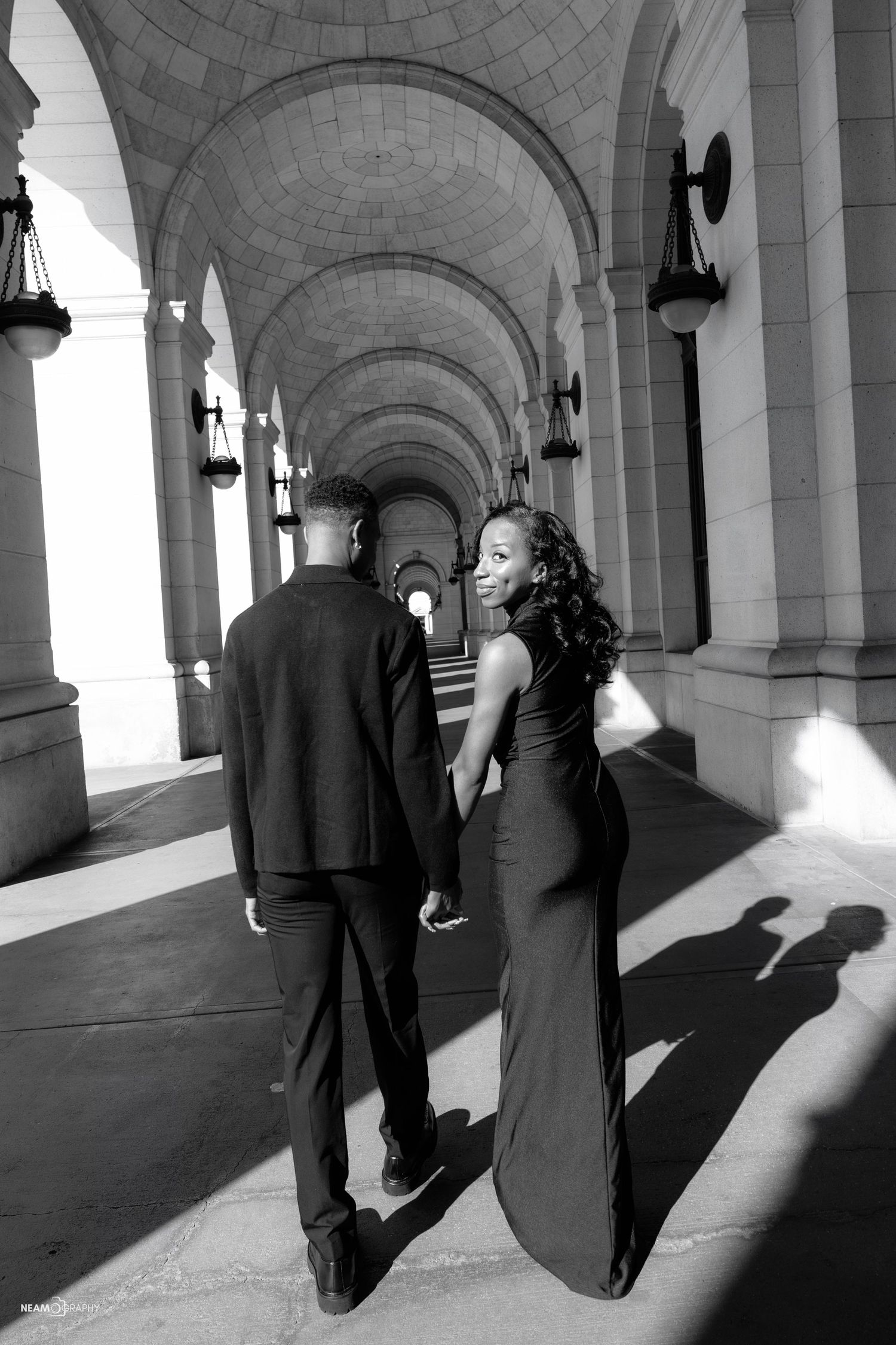 Gay engagement session at Union Station in Washington DC featuring a couple walking together through the iconic historic arches.