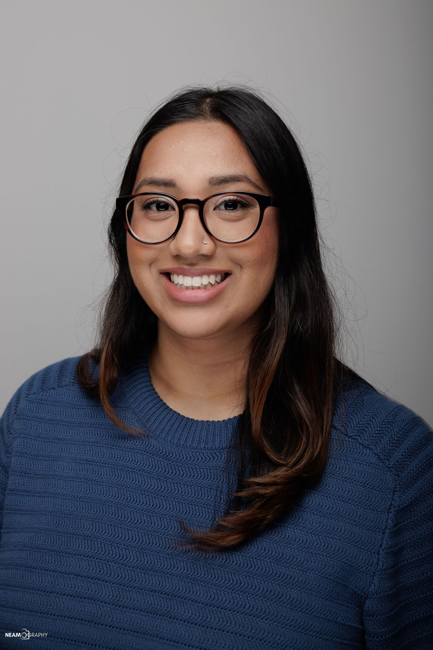 Professional corporate headshot of a smiling woman with glasses in Bethesda, MD. Corporate branding photography by Neamography.