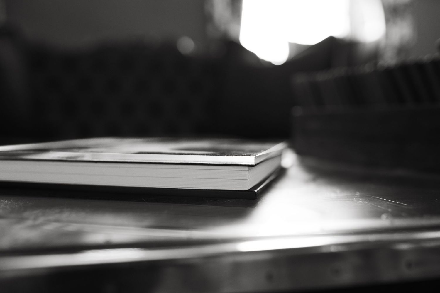 A blurred black and white close-up of a book or notebook on a reflective surface.