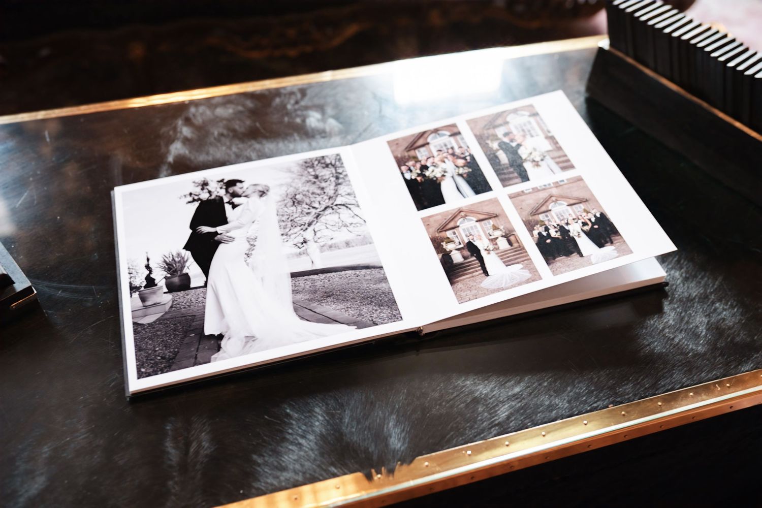 An array of black and white wedding photo albums laid out horizontally on a dark wooden surface.