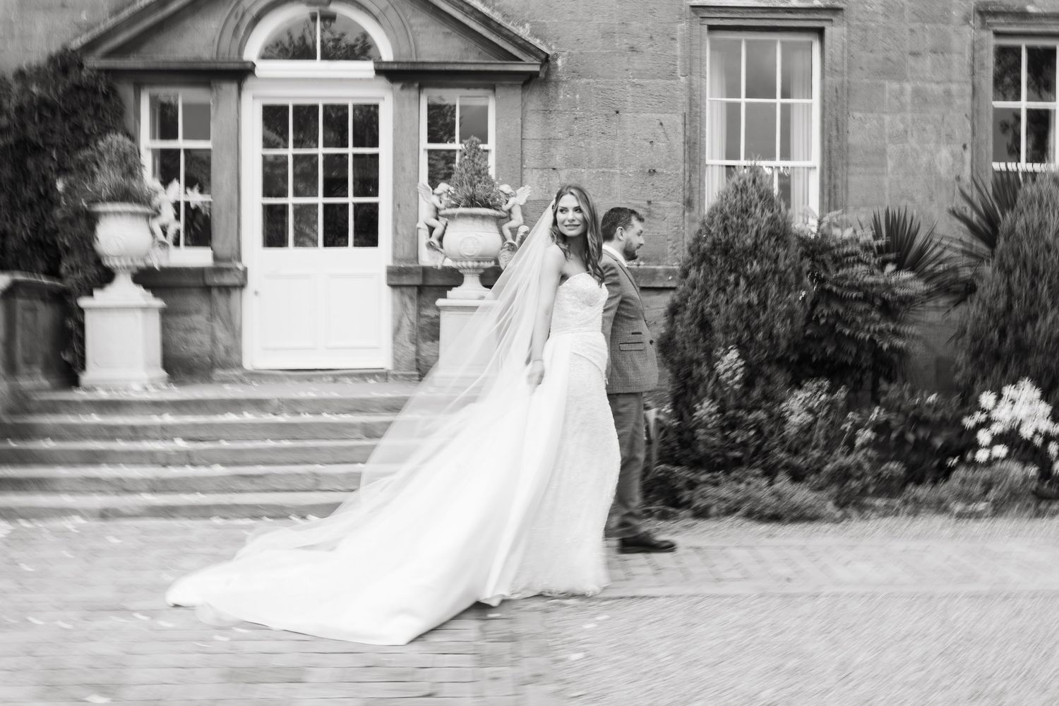 A collection of black and white wedding photographs showing happy moments outside a grand stone building.