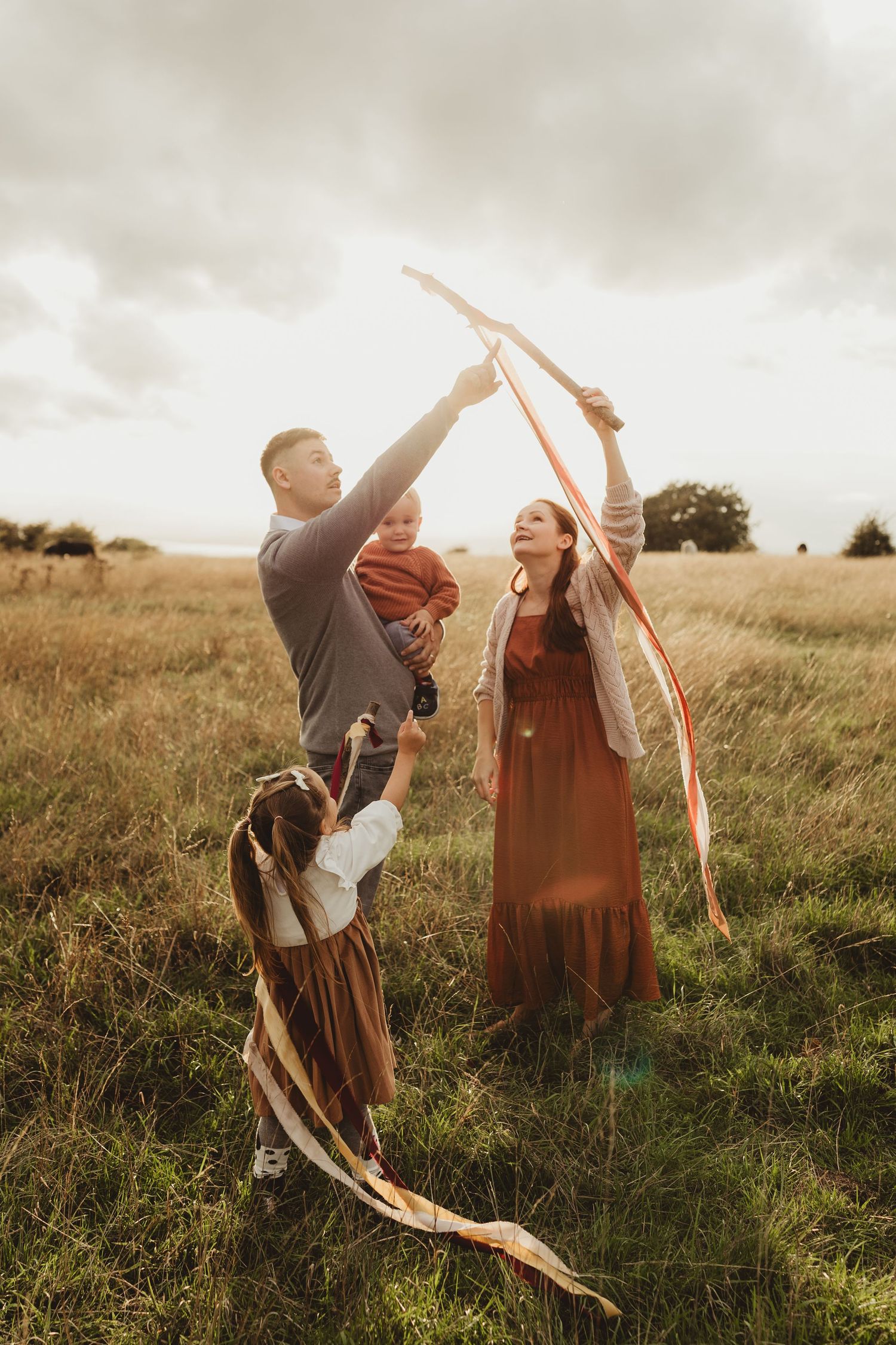 A couple dances together in a grassy meadow at sunset, creating a romantic and whimsical atmosphere.