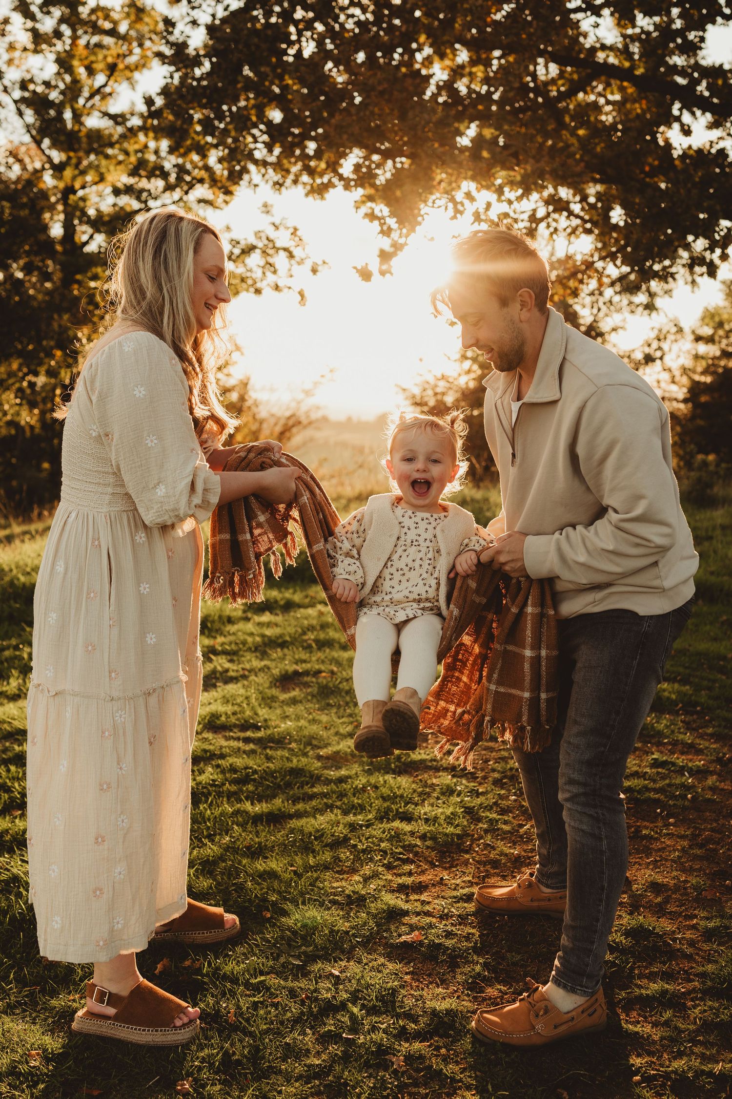 A series of candid outdoor family photos taken at sunset showing tender moments between parent and child on a grassy hill.