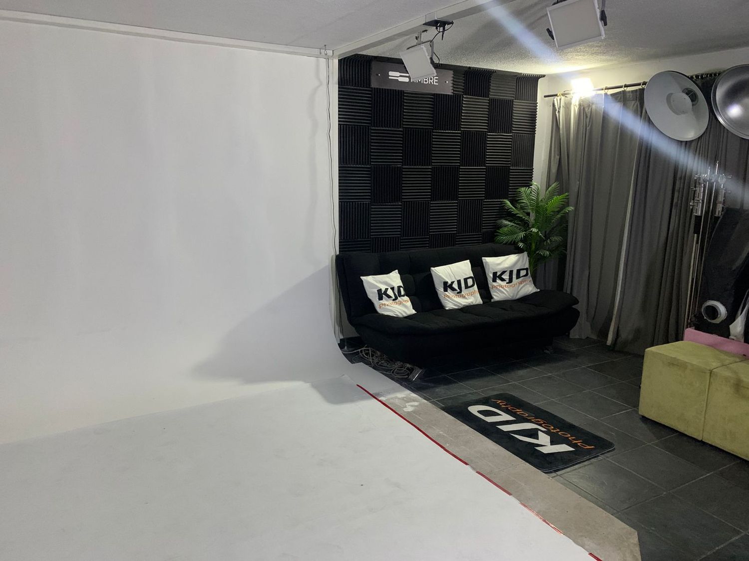 Modern multimedia studio featuring acoustic panels, monitors, and professional recording equipment with black and white decor.