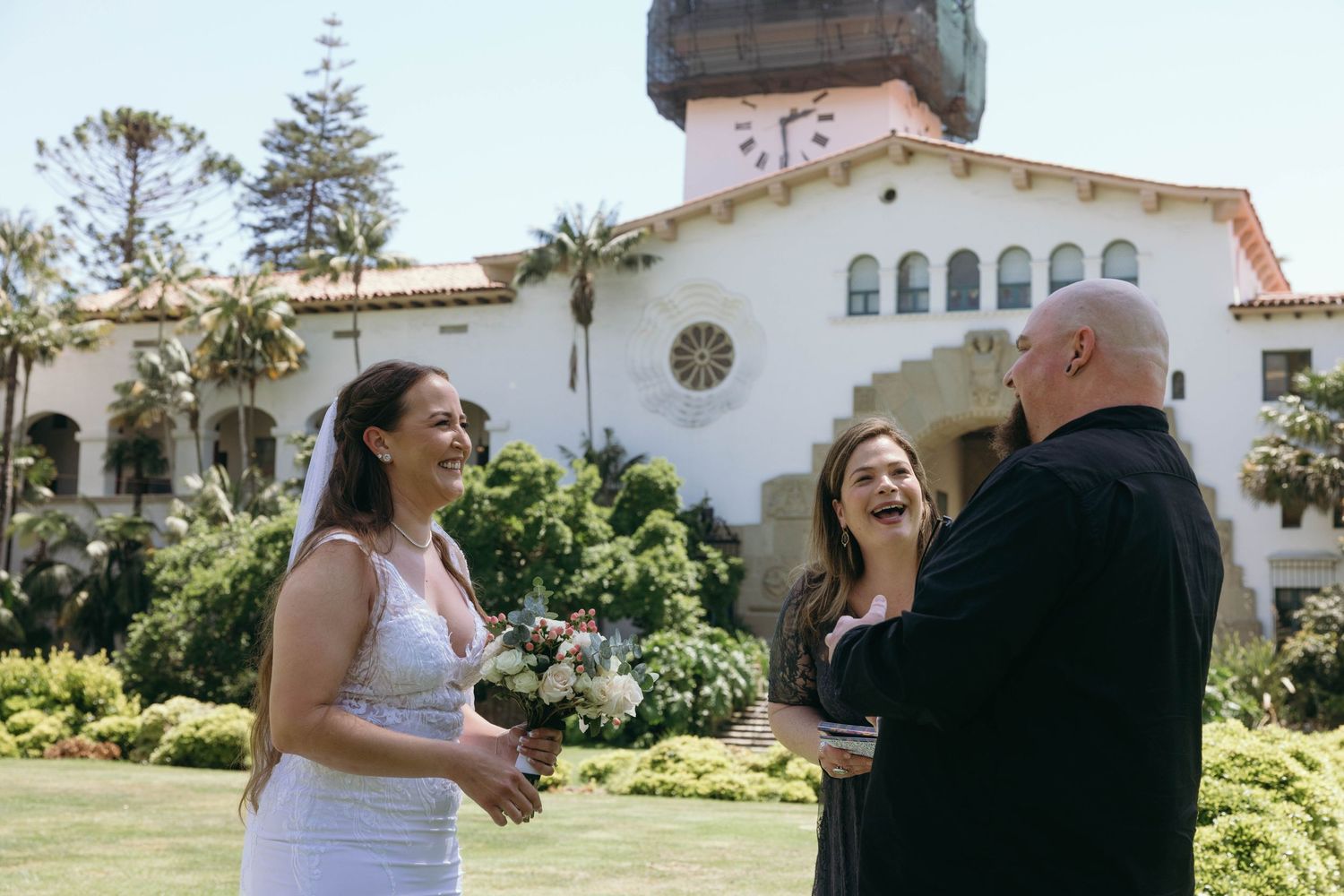 Joyful moment captured in front of a Spanish-style building with white walls and red tile roof.