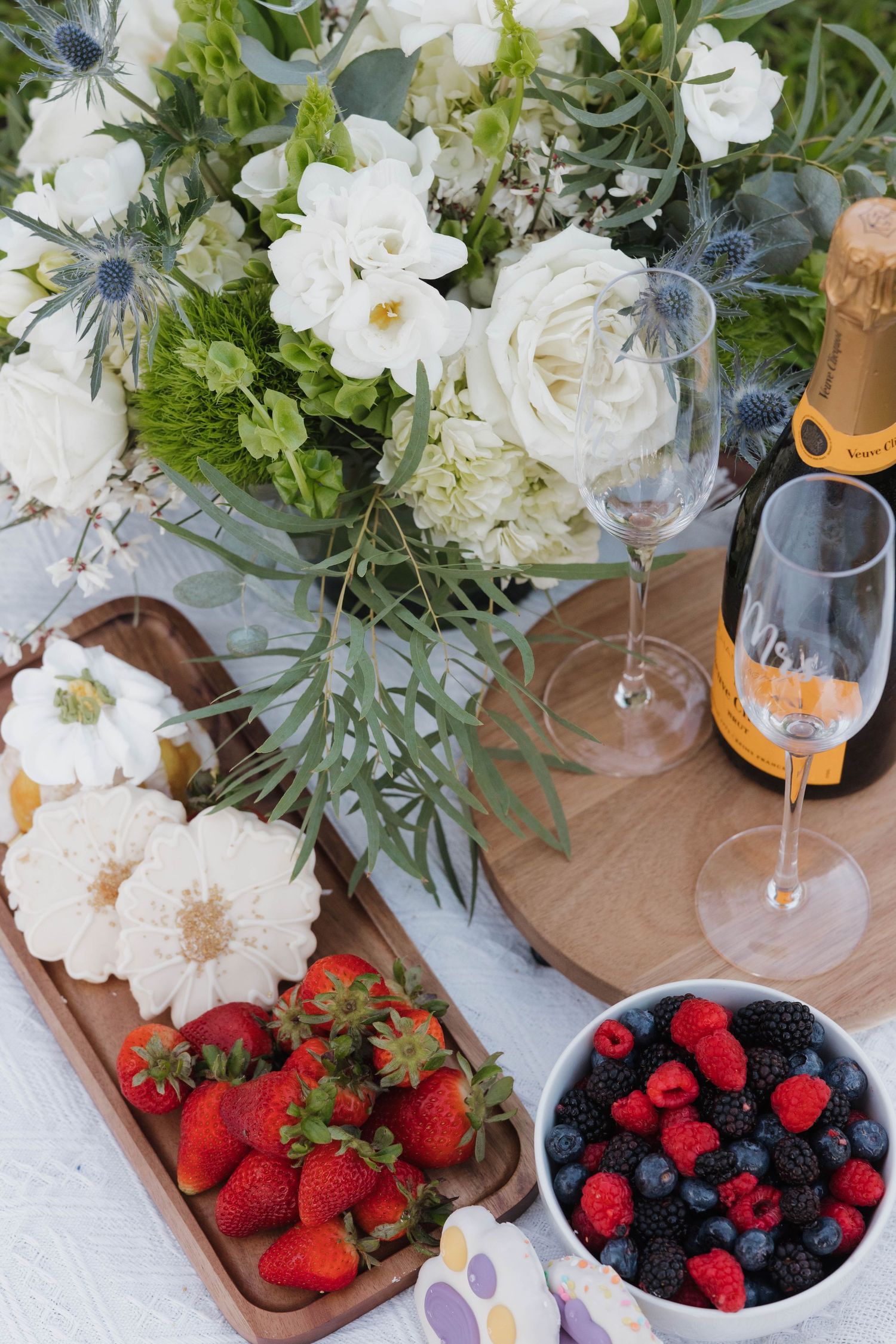 Elegant table setting with white flowers, berries, and champagne glass.