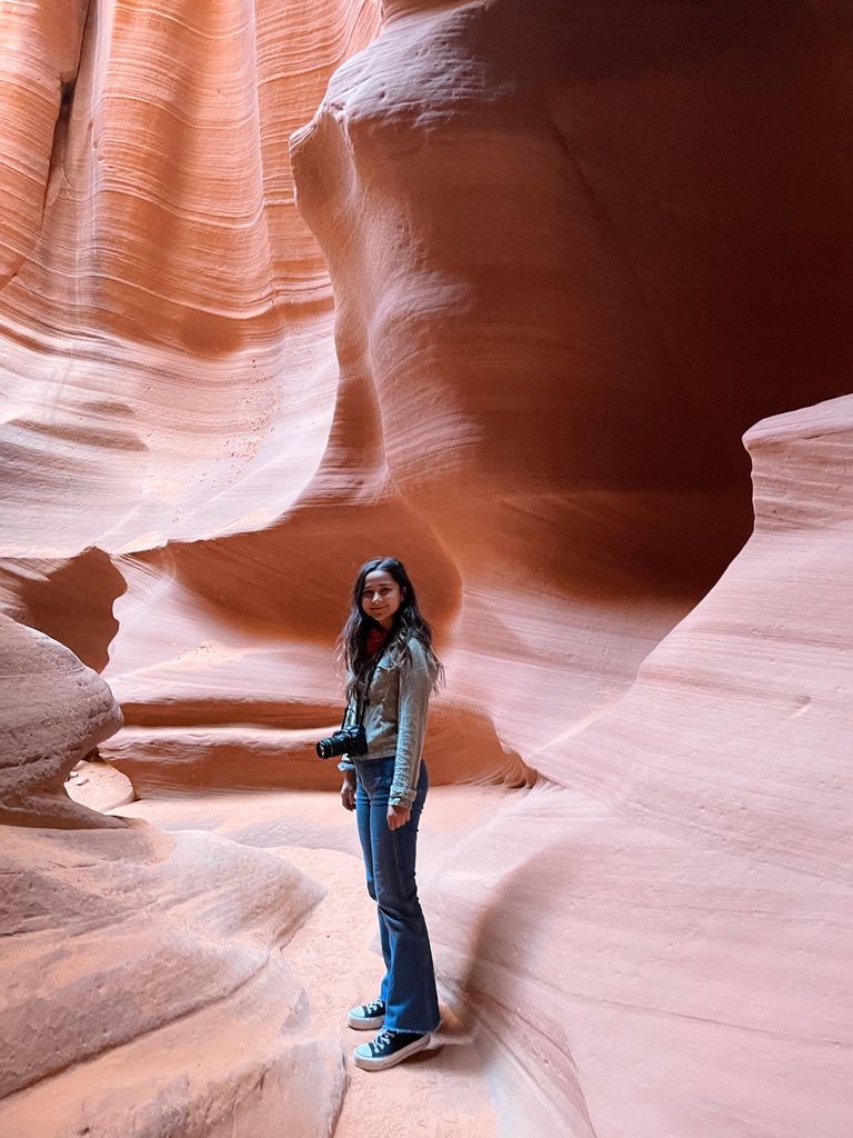 A photographer explores the smooth curves and orange walls of Antelope Canyon.