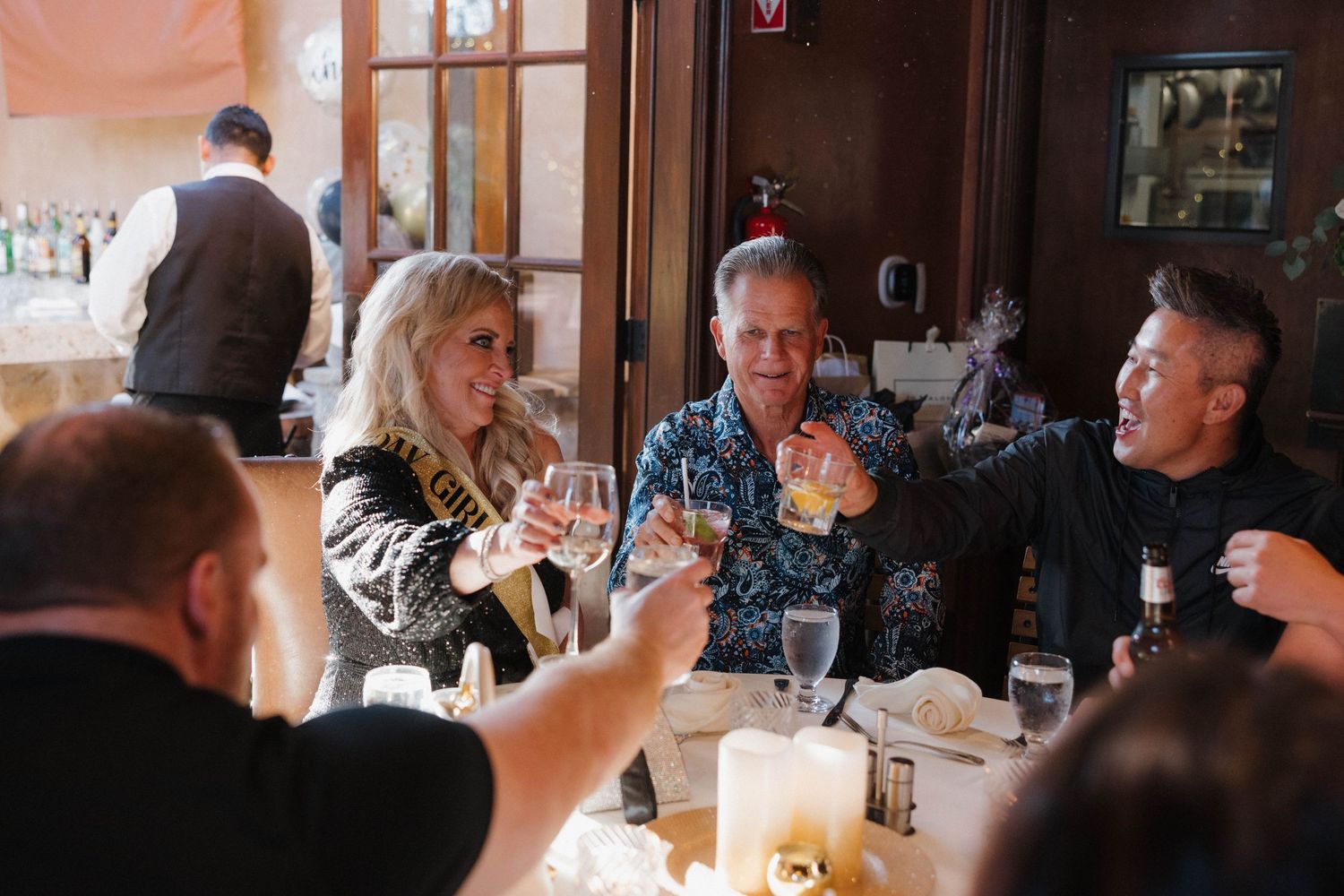 A group dining at a restaurant table with drinks and candlelight during an evening gathering.