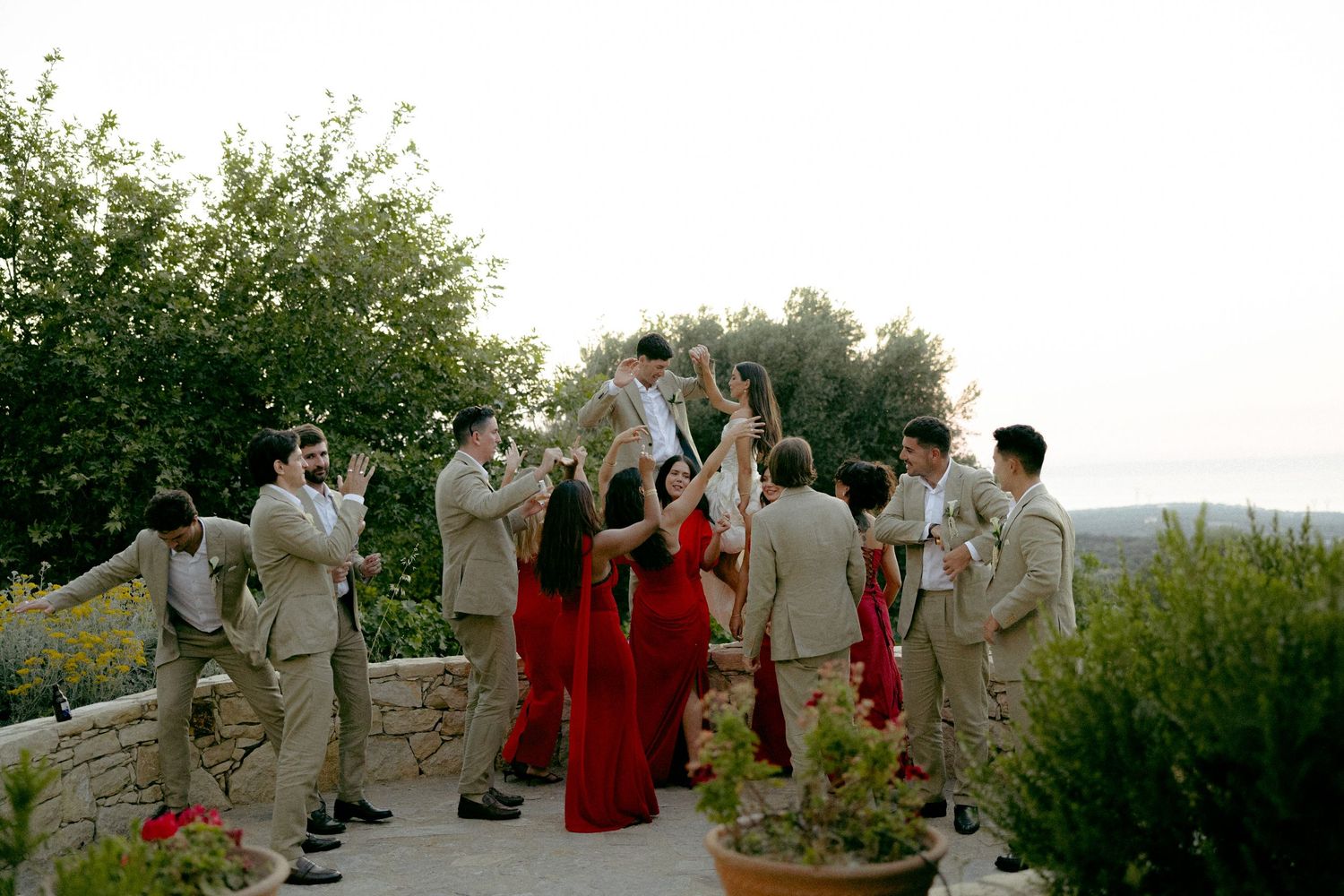 Wedding guests dance and celebrate together at an outdoor reception with scenic mountain views in the background.