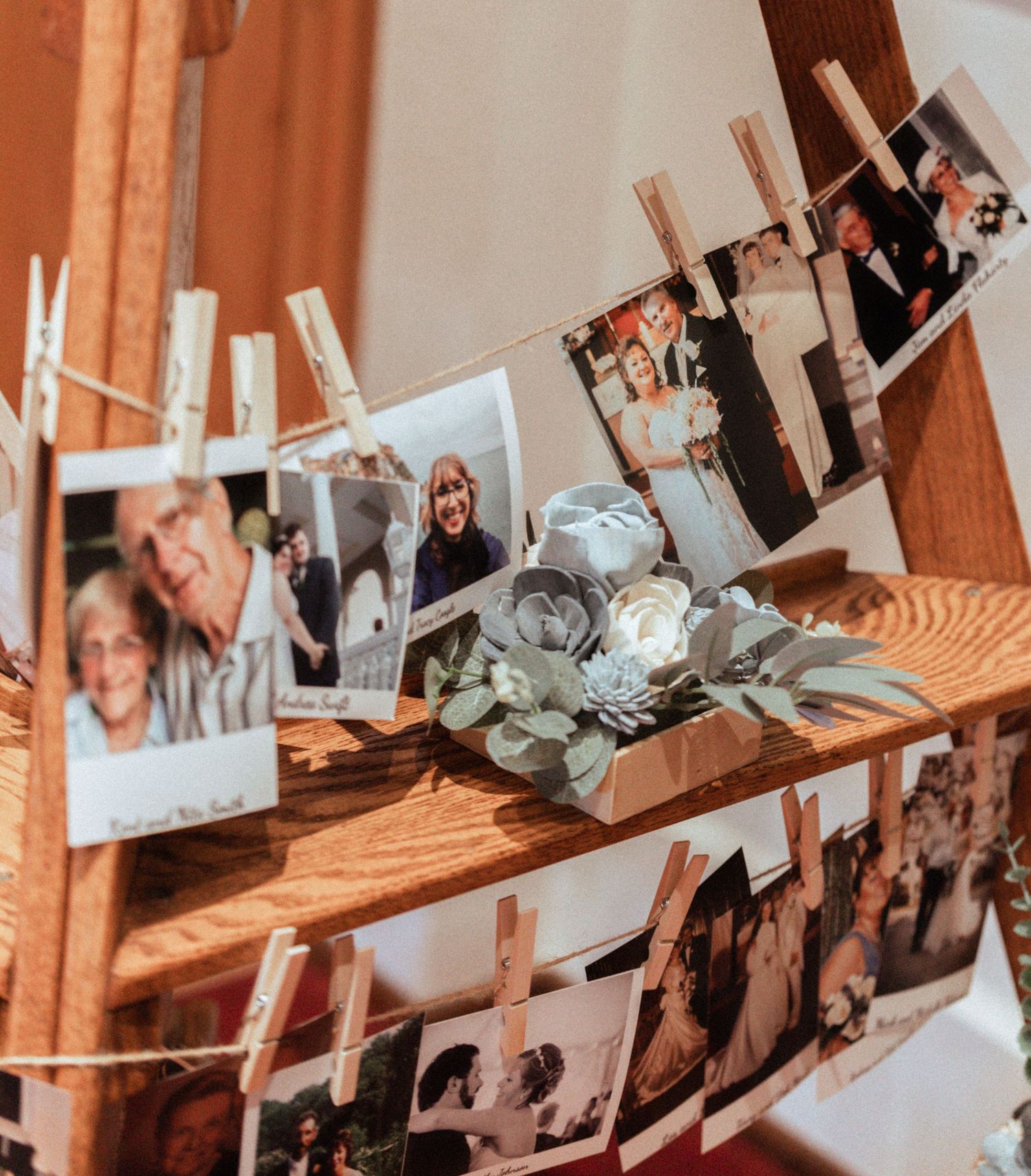 Rustic wooden ladder display with polaroid photos clipped by clothespins and a floral centerpiece at a wedding reception.