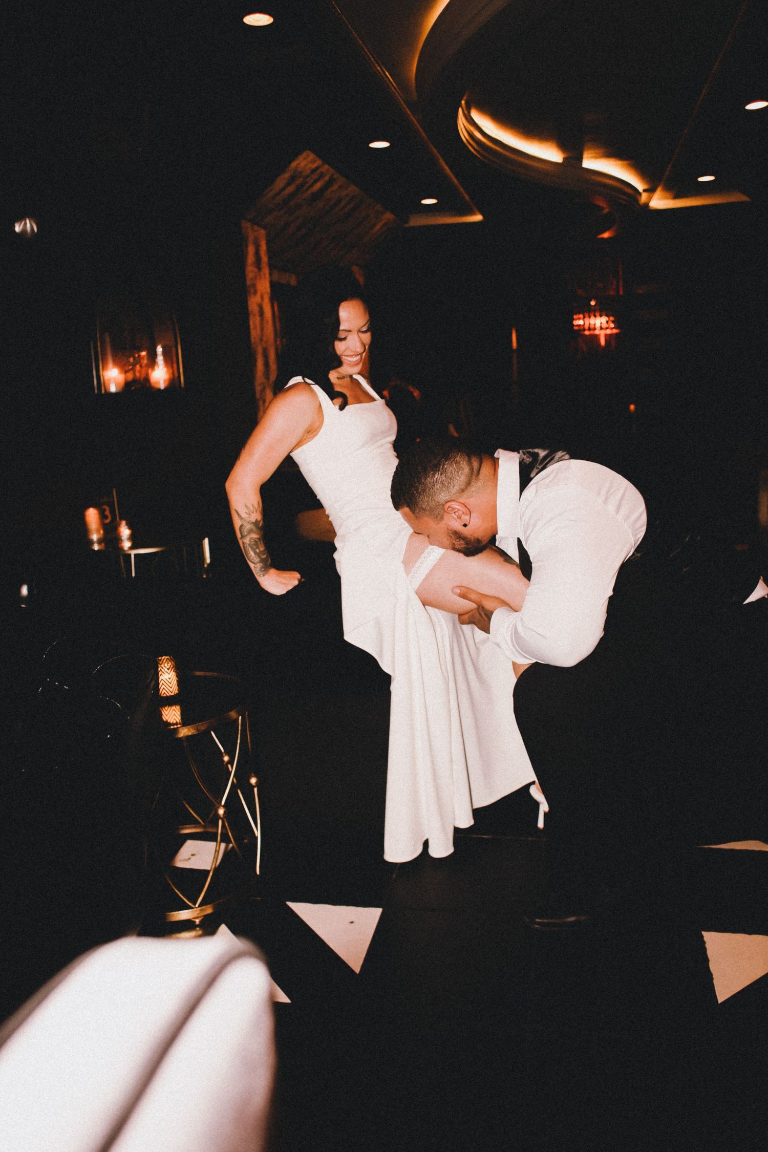 Bride and groom sharing an intimate first dance moment in a dimly lit wedding reception venue.