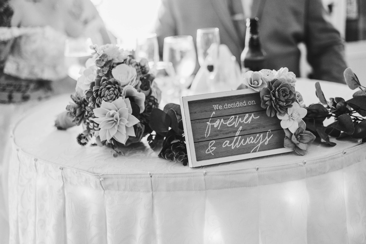 Black and white wedding reception table with floral arrangement and forever and always sign.