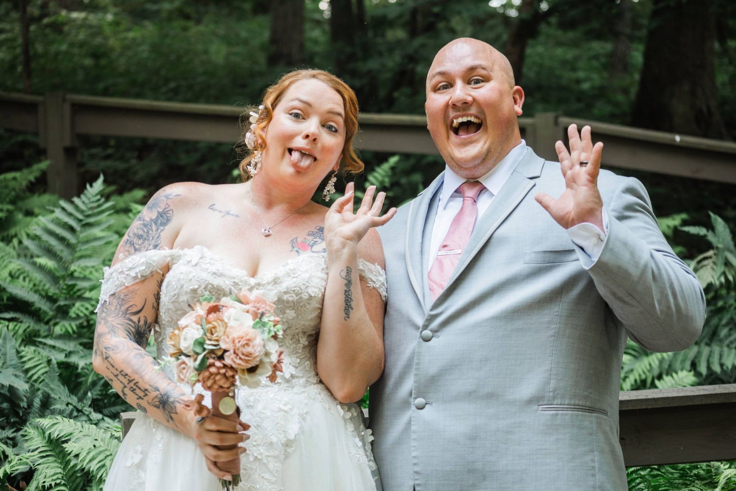 Joyful bride and groom showing off their wedding rings with excited expressions outdoors.