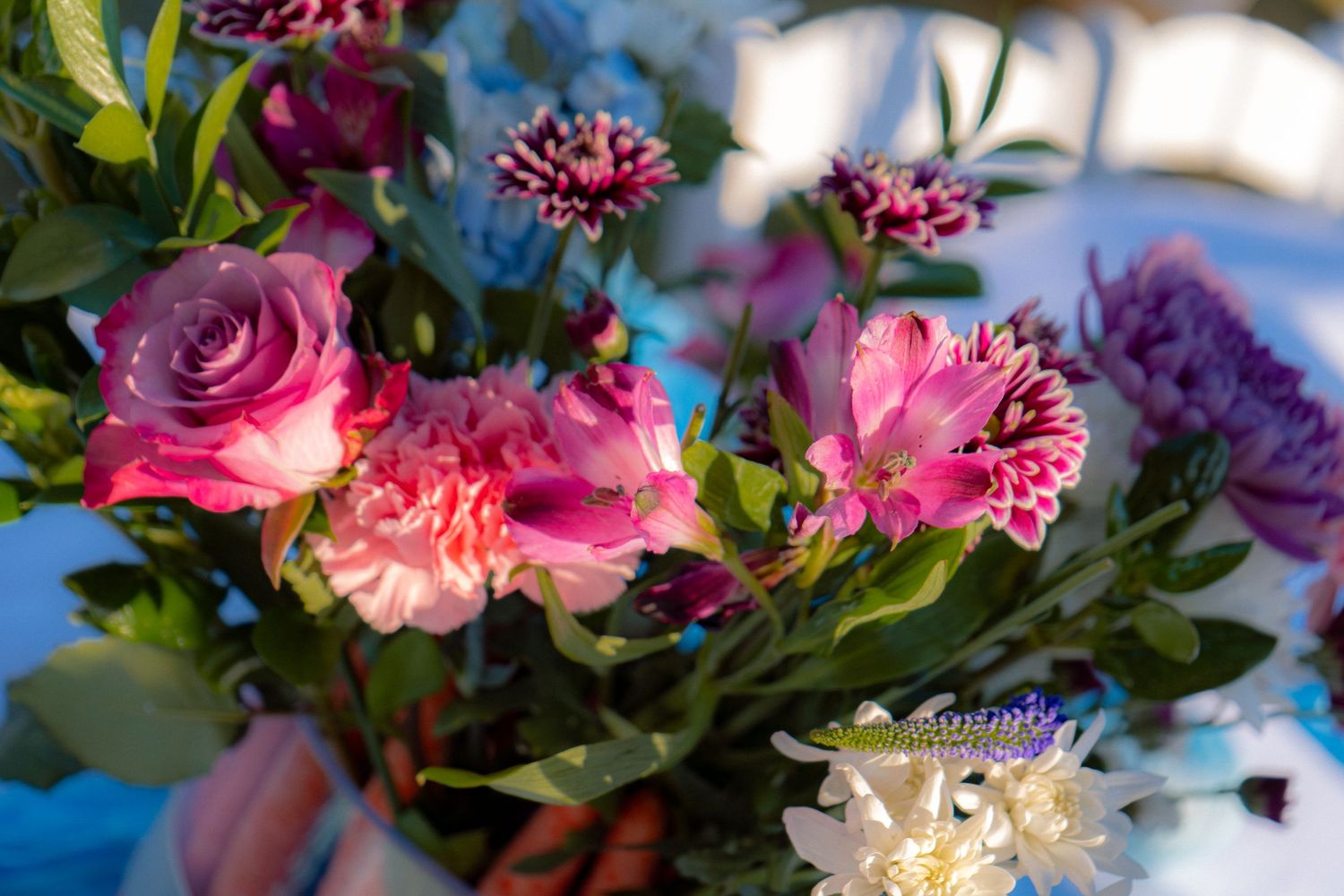 Close-up of a beautiful bouquet featuring pink roses, carnations, purple alstroemeria, and magenta chrysanthemums.
