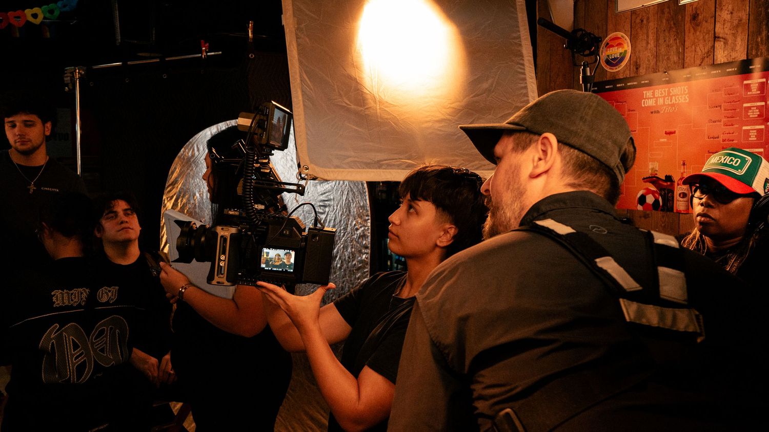 Film crew members examine a professional camera on a dimly lit movie production set.