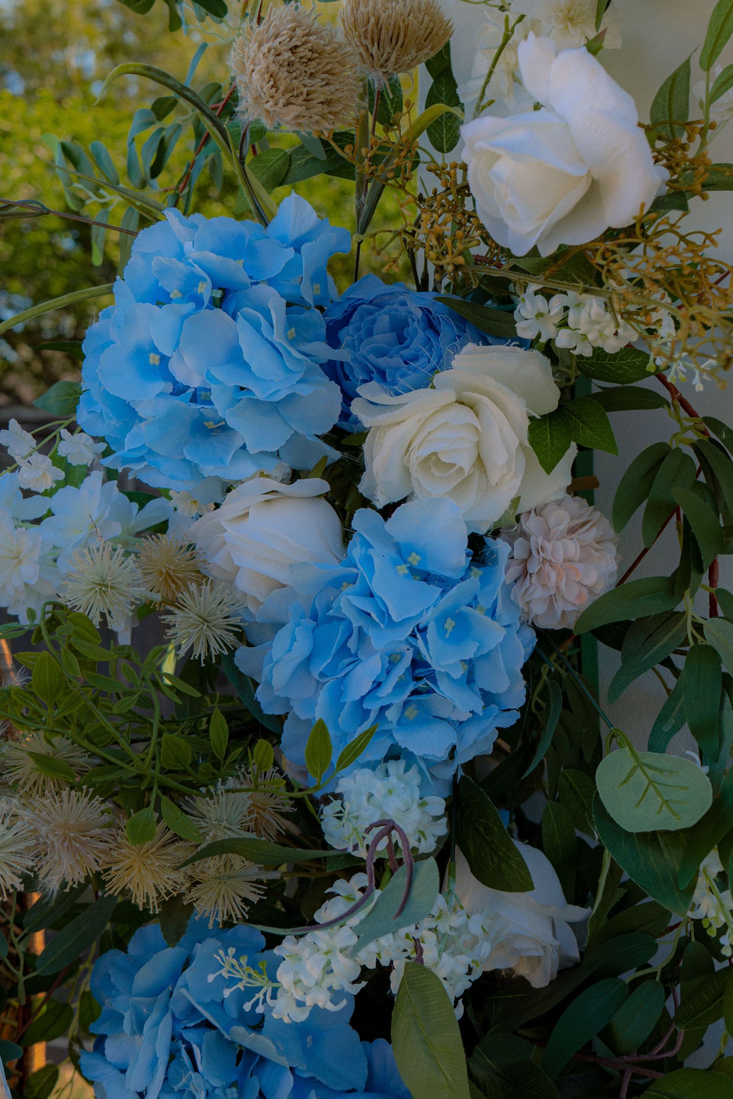 Close-up of blue hydrangeas and white roses floral arrangement for a baby shower event outdoors.