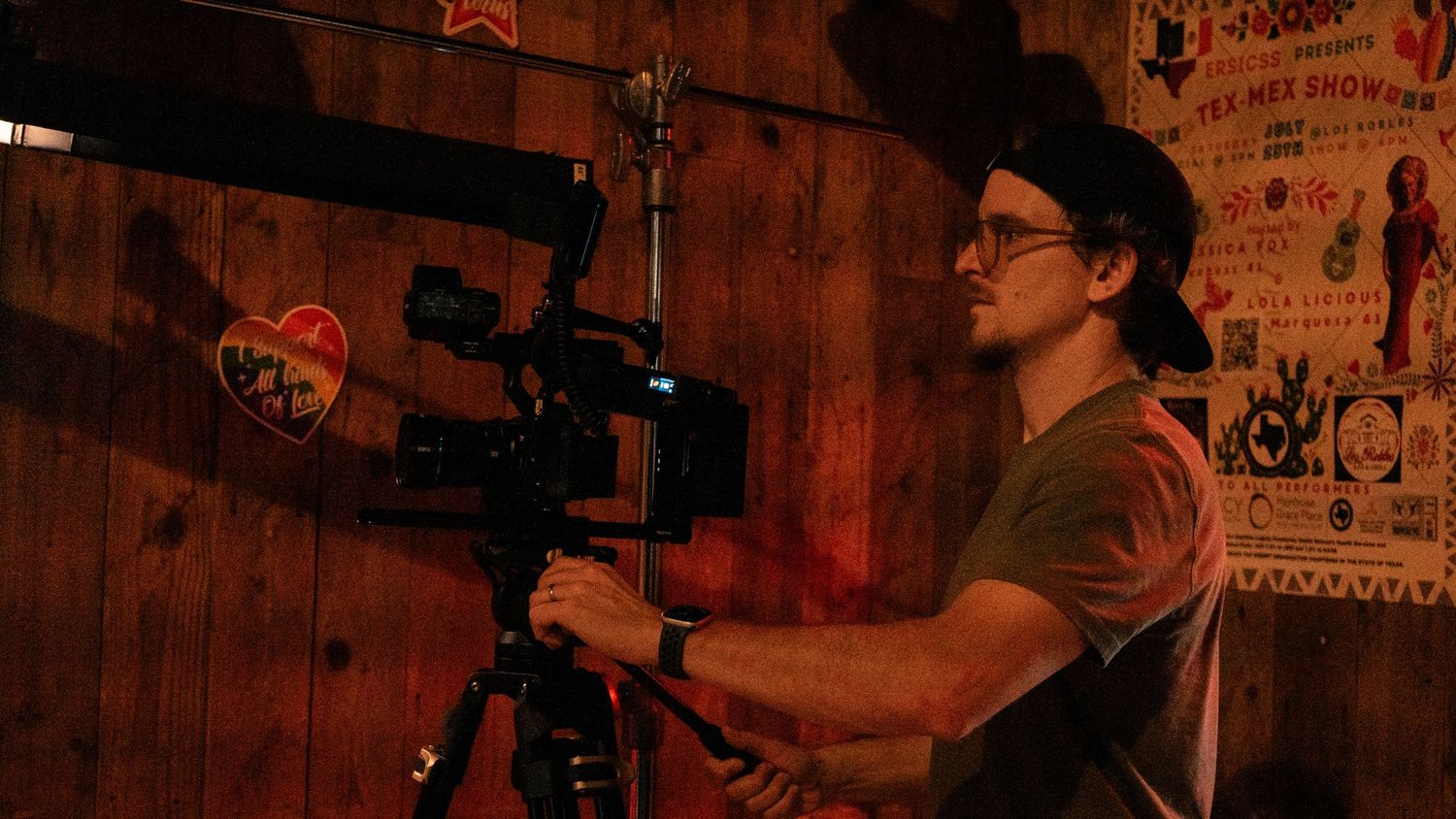 A filmmaker operates a camera on a stabilizer rig in a dimly lit rustic interior.