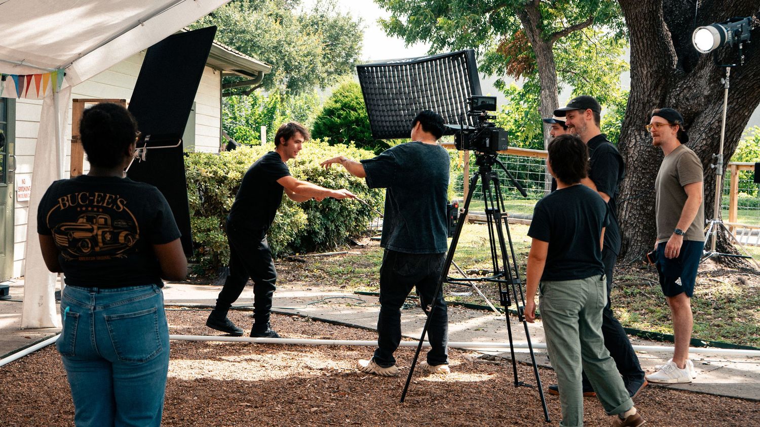 Film crew setting up lighting equipment outdoors for a video production shoot in a park setting.