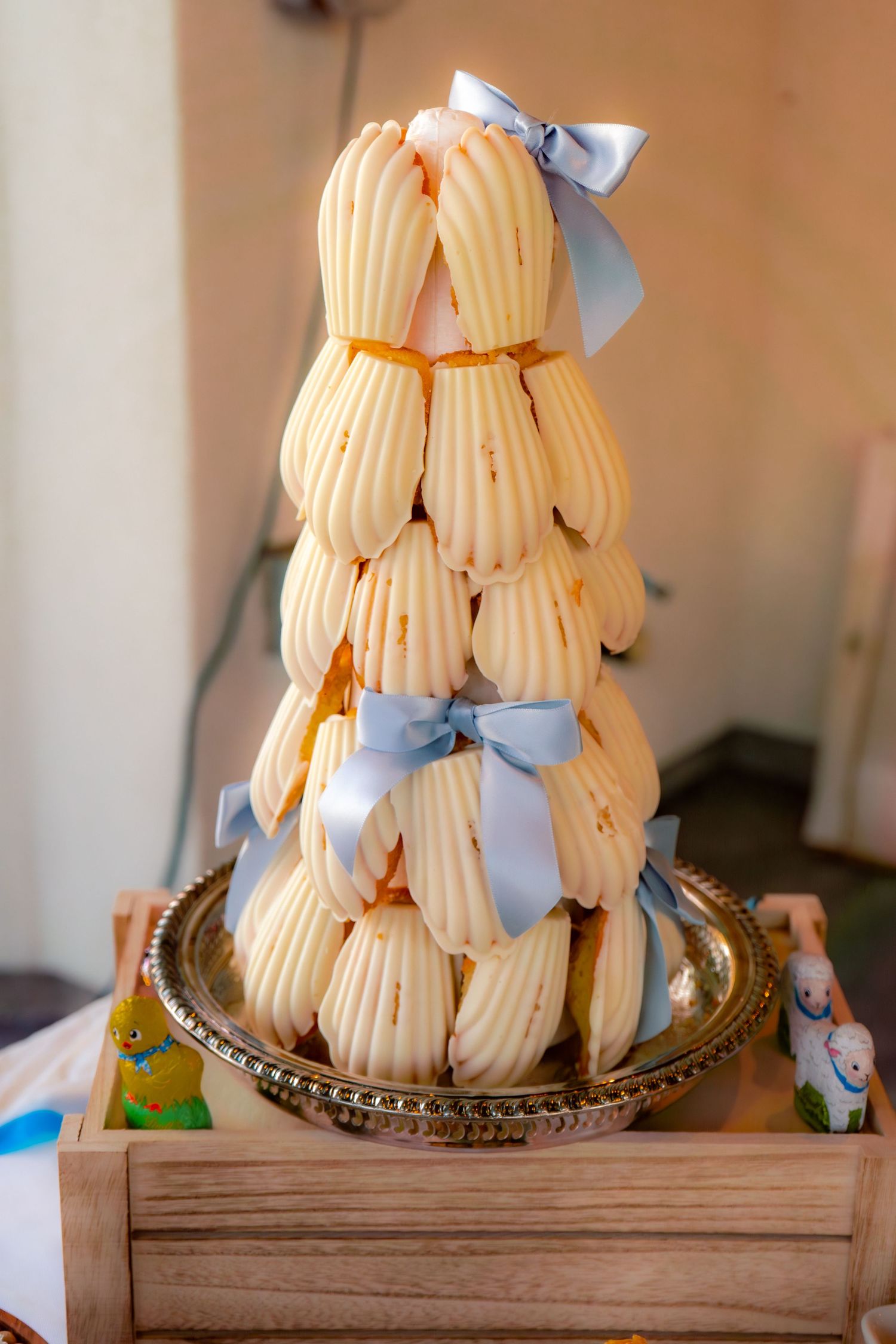 Elegant tower of cream-filled pastry shells tied with light blue satin ribbons on a silver tray.